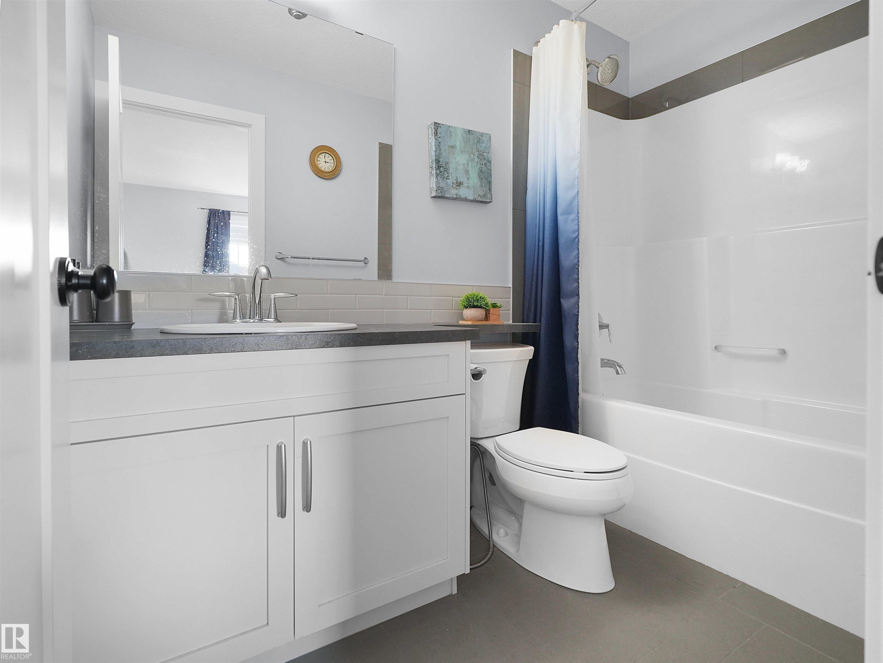 Vanity with a rectangular undermount sink, gray countertop, and brushed nickel faucet - 6656 Cardinal Rd Sw, Edmonton, AB