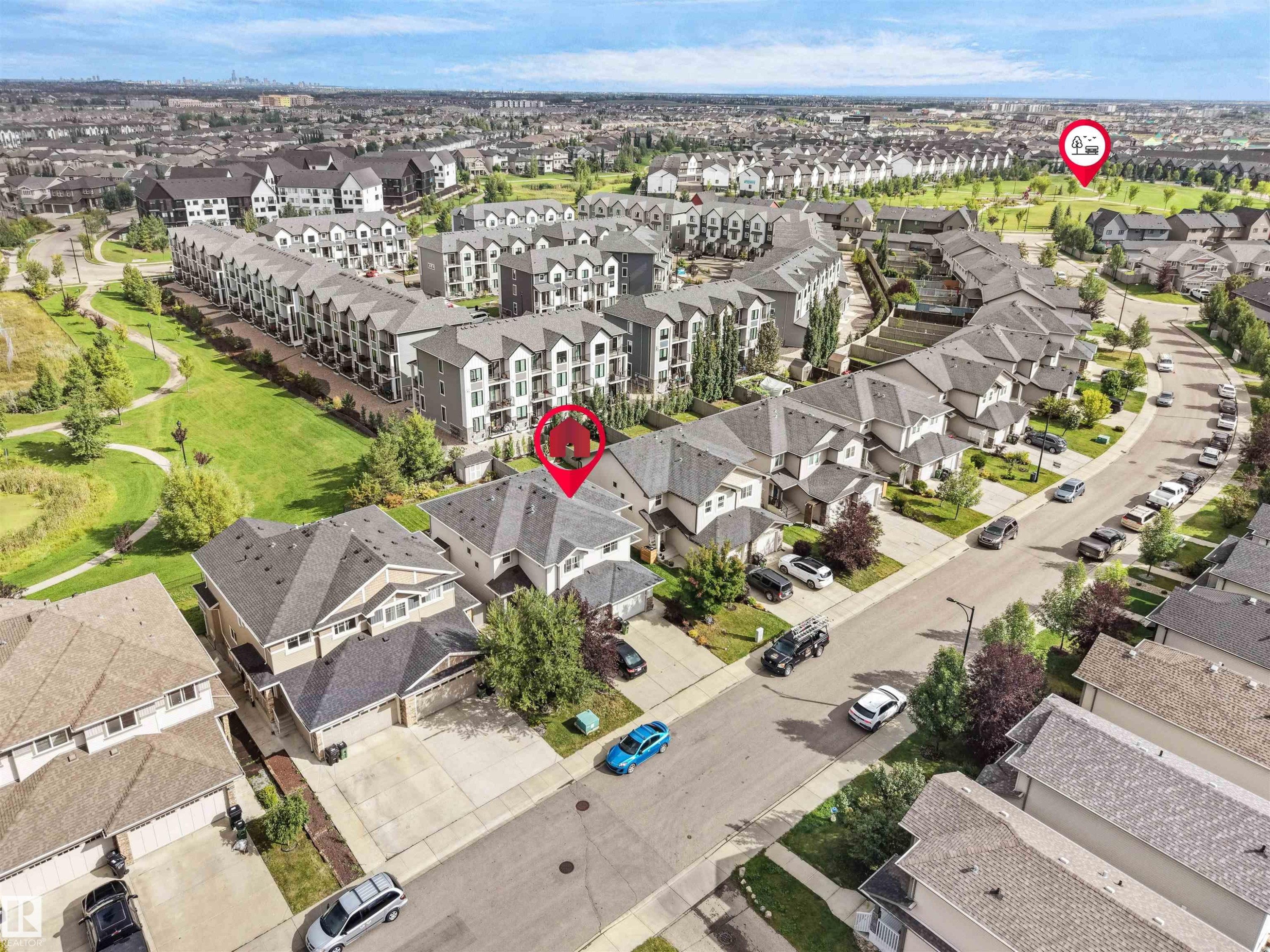 Residential neighborhood with varied housing styles including single-family homes and multi-story townhomes, surrounded by green spaces and paved roadways - 6656 Cardinal Rd Sw, Edmonton, AB