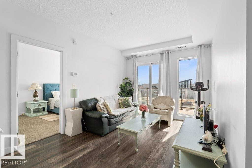 Living area with wood-finish flooring, white walls, and a recessed ceiling feature - 1316 Windermere Way Sw, Edmonton, AB