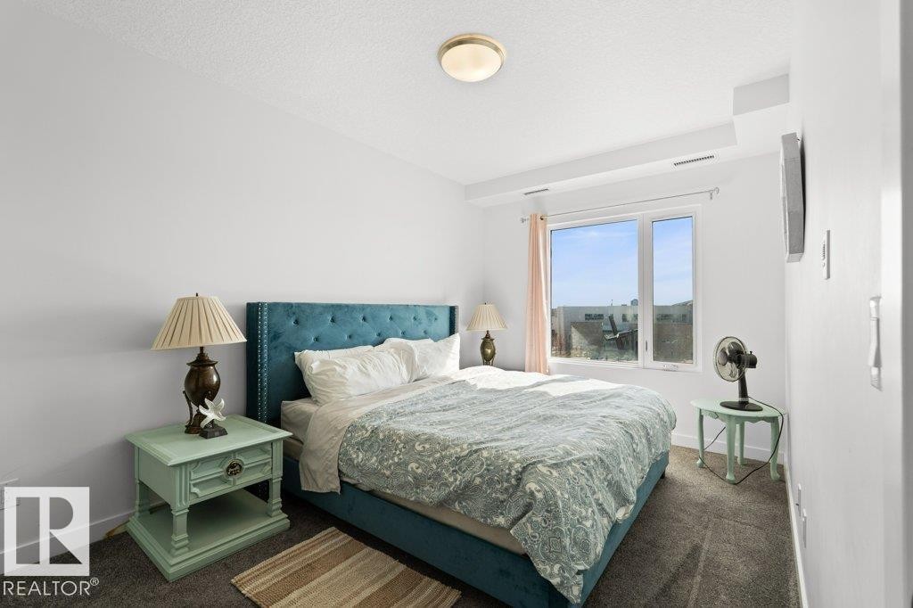 Bright bedroom featuring a large window, neutral wall paint, and gray carpet flooring - 1316 Windermere Way Sw, Edmonton, AB