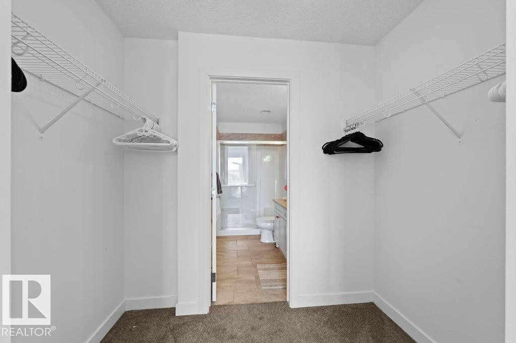 Walk-in closet with wire shelving and plush carpet flooring - 1316 Windermere Way Sw, Edmonton, AB