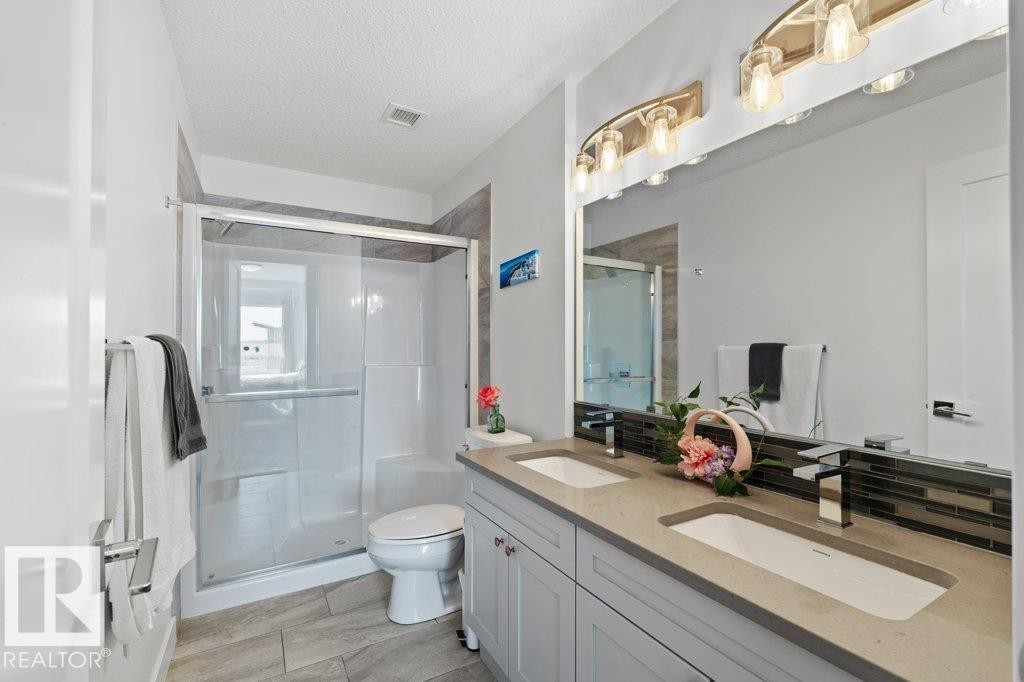 Bathroom featuring a dual vanity with light-toned countertops, integrated sinks, and polished chrome faucets - 1316 Windermere Way Sw, Edmonton, AB