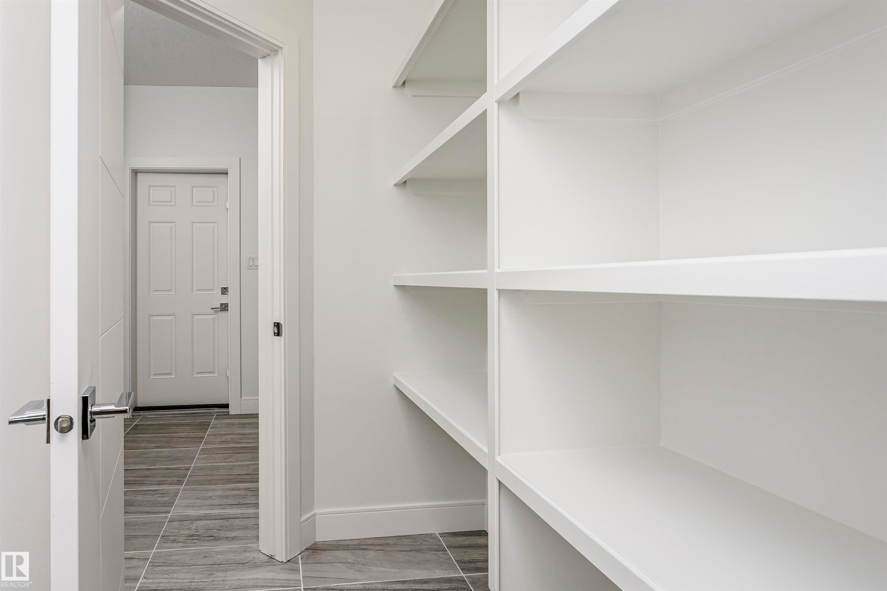 Built-in shelving with white finish, modern interior door with horizontal paneling, and rectangular tile flooring - 9107 181 Avenue Nw, Edmonton, AB