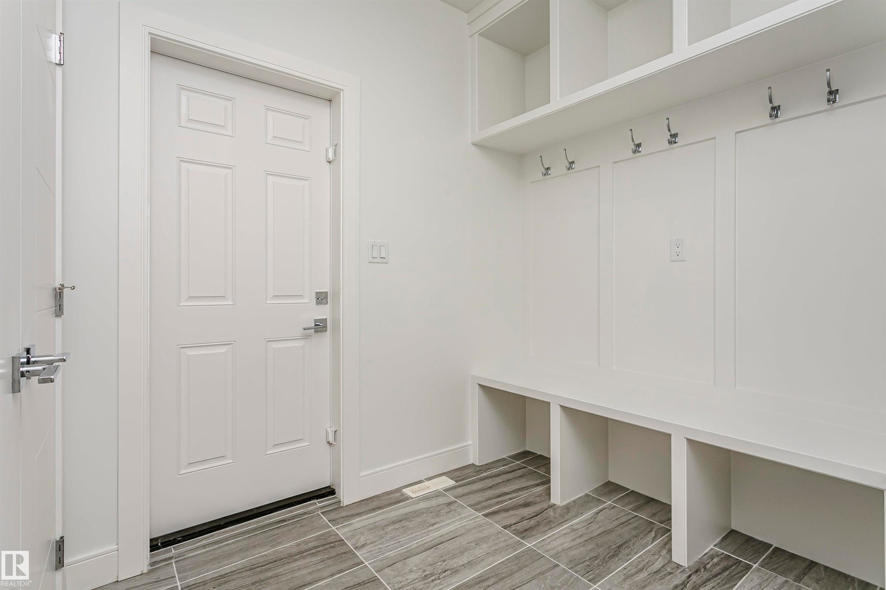 Built-in bench seating with storage, integrated wall hooks, overhead shelving, and large format floor tiling - 9107 181 Avenue Nw, Edmonton, AB
