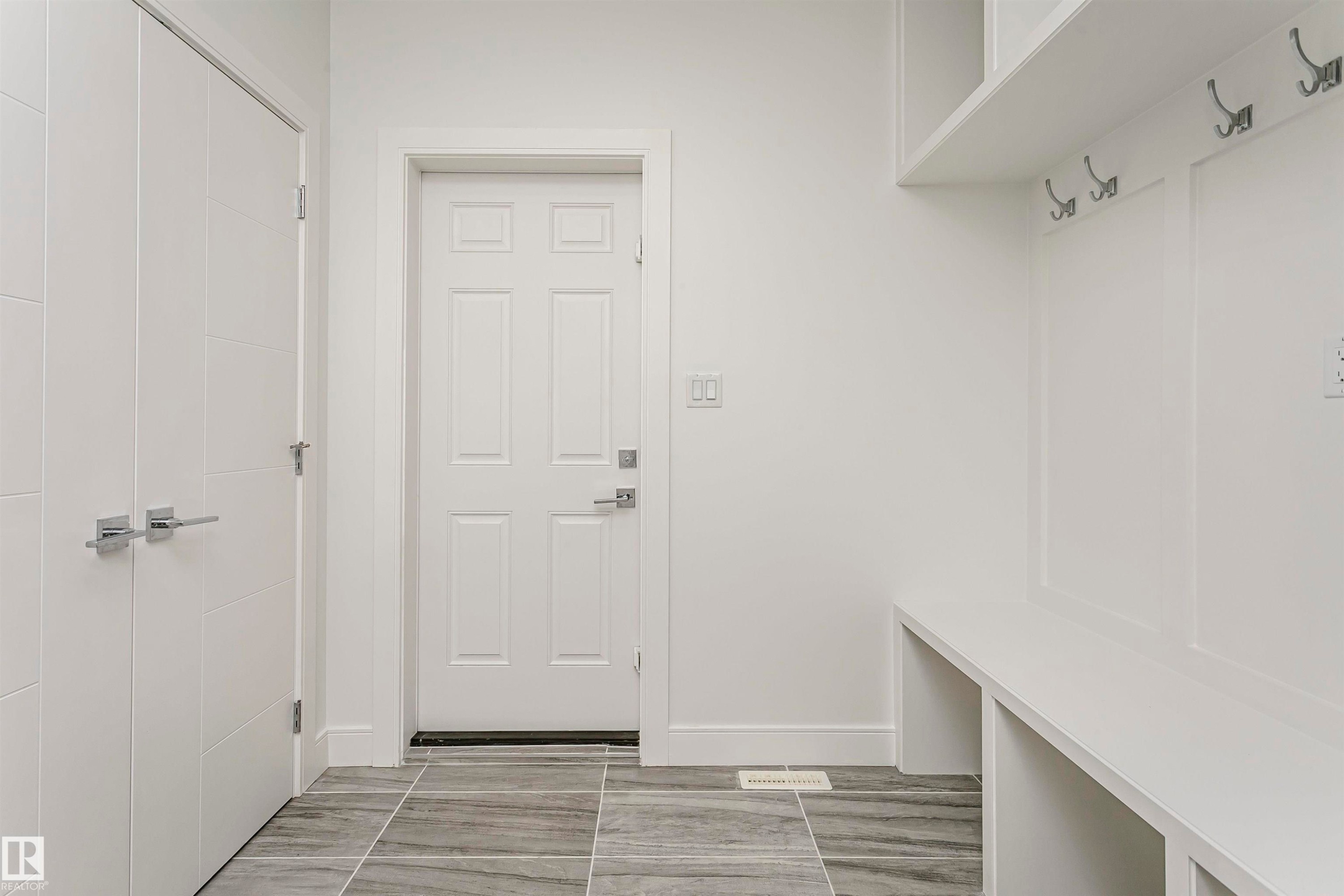 Built-in bench seating with storage, integrated wall hooks, and modern white trim - 9107 181 Avenue Nw, Edmonton, AB