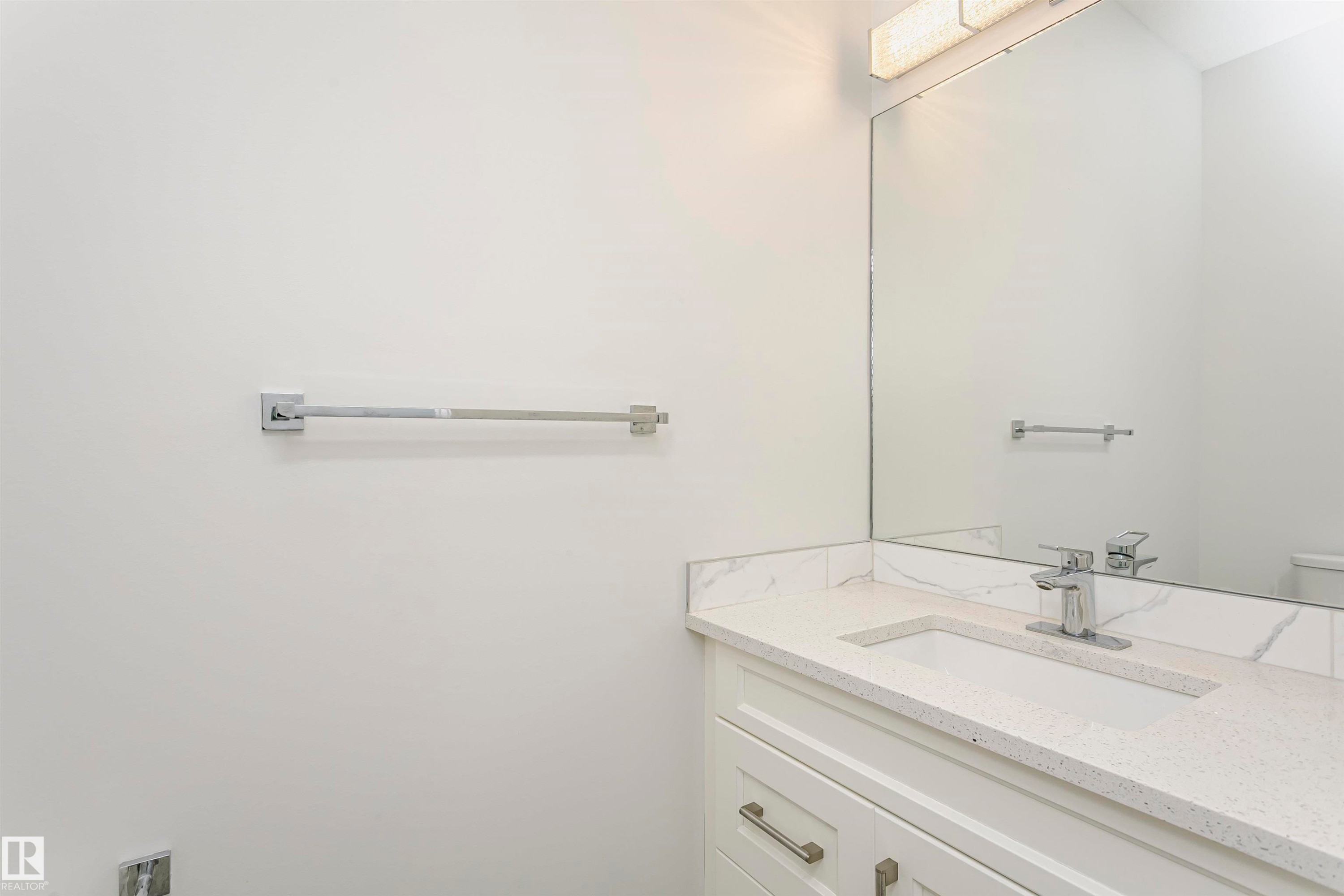 White vanity with chrome hardware, an integrated rectangular sink, and a speckled countertop - 9107 181 Avenue Nw, Edmonton, AB