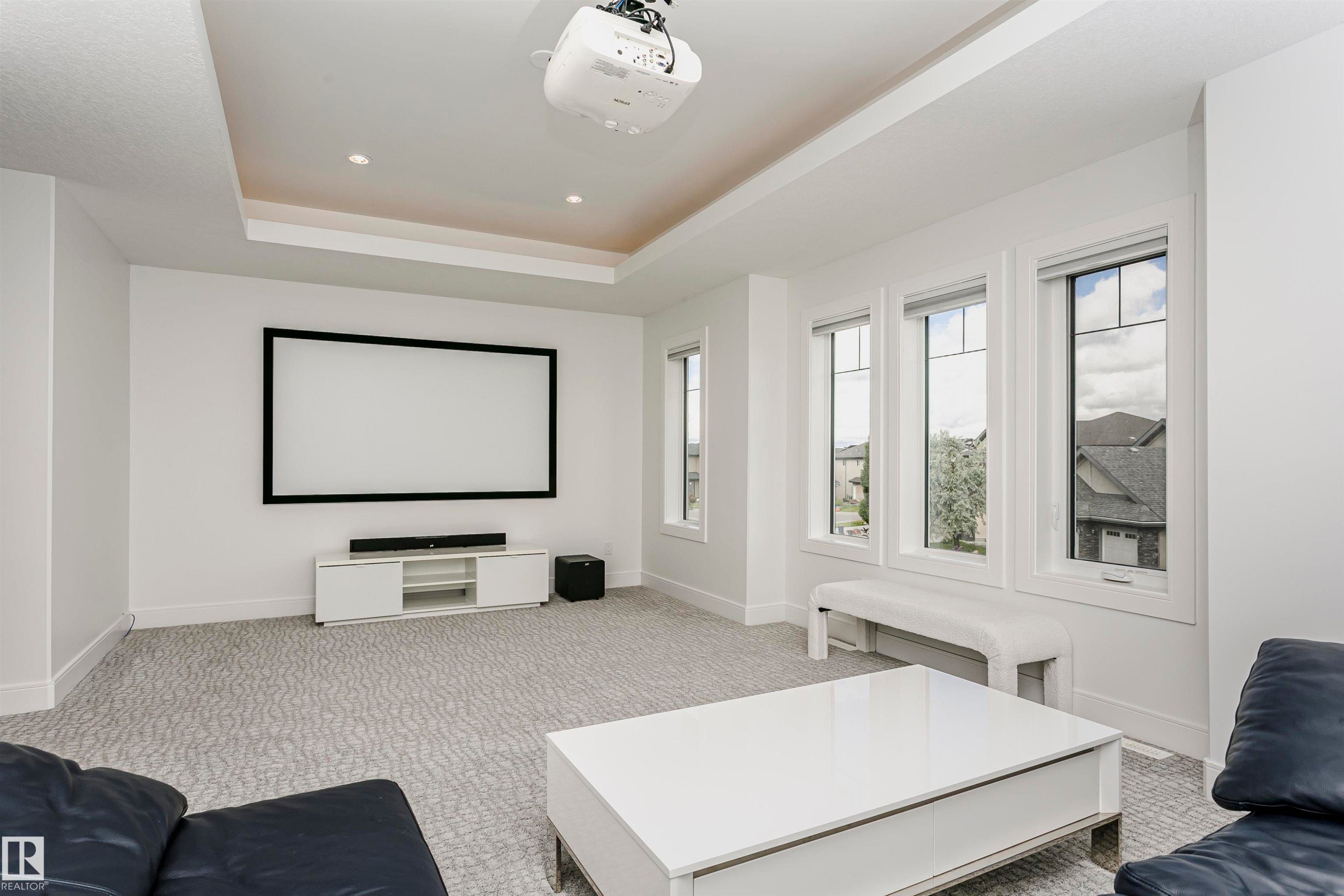 Recessed lighting, tray ceiling, integrated projection screen, multiple windows, and patterned carpeting - 9107 181 Avenue Nw, Edmonton, AB