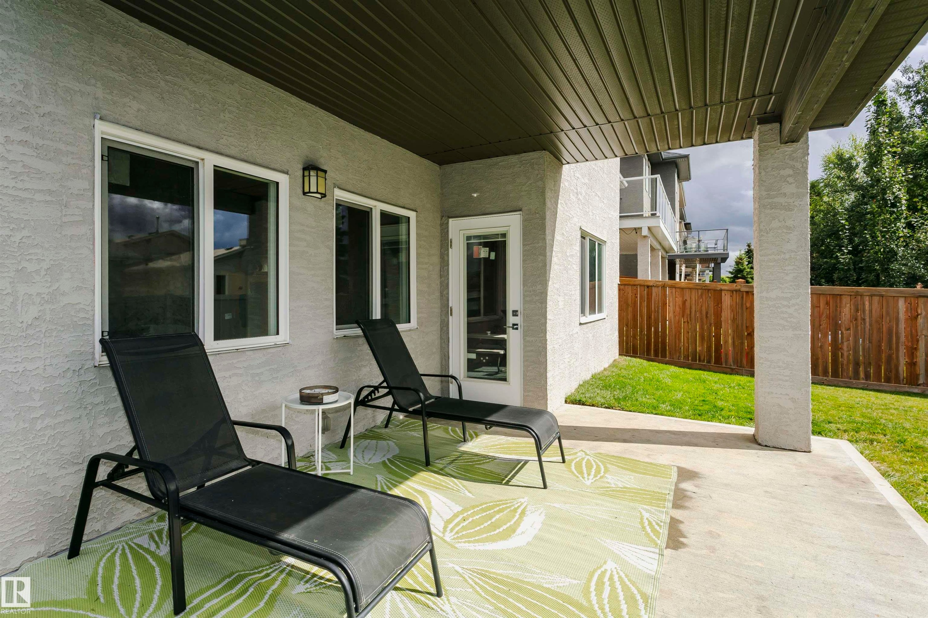 Covered concrete patio with white stucco exterior and permanent outdoor lighting - 9107 181 Avenue Nw, Edmonton, AB