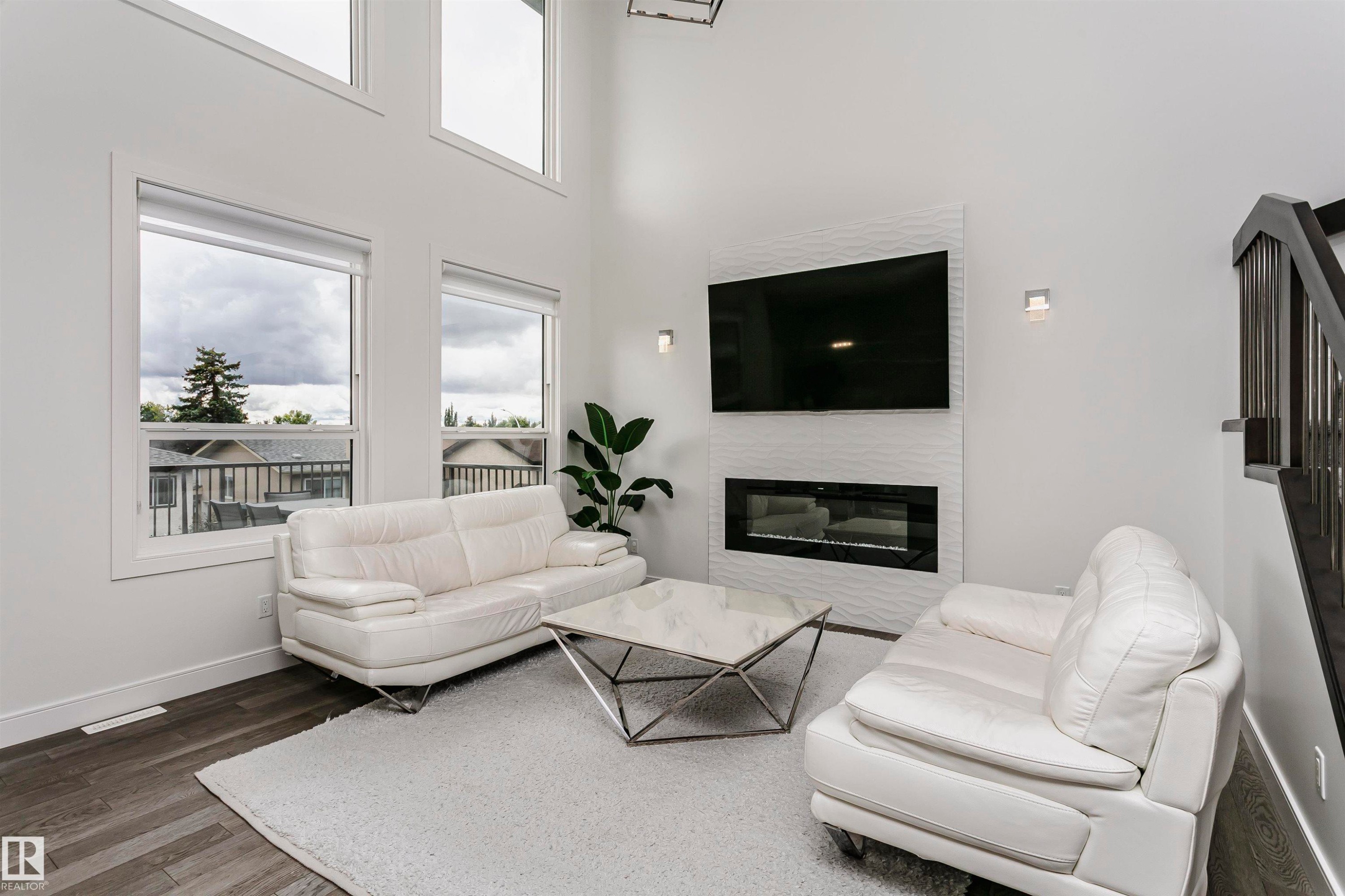 Soaring ceilings, wood-finish flooring, and multiple large windows provide abundant natural light - 9107 181 Avenue Nw, Edmonton, AB
