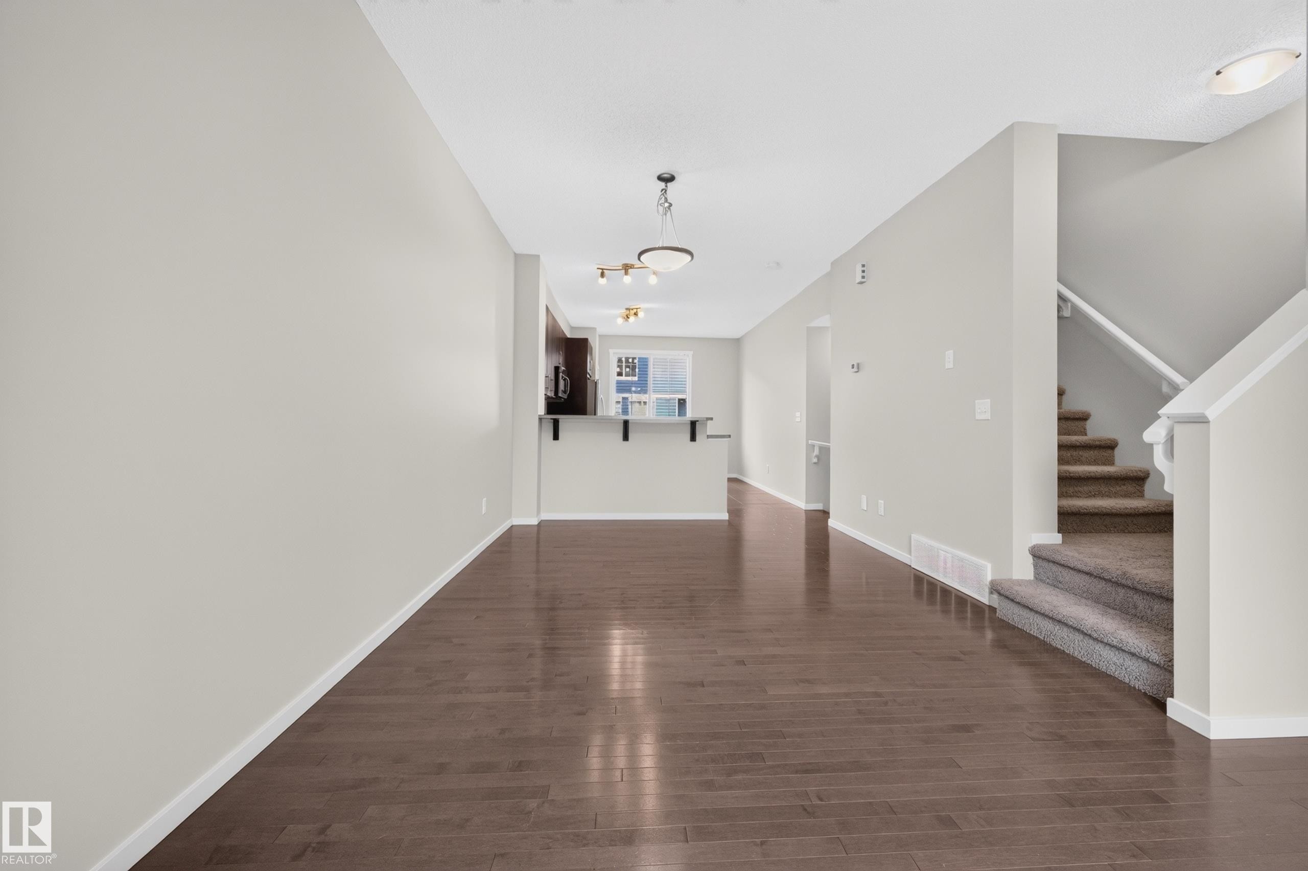 Wood-finish flooring, light-toned wall paint, recessed lighting, and a staircase with carpeted treads - #72 603 Watt Bv Sw Sw, Edmonton, AB