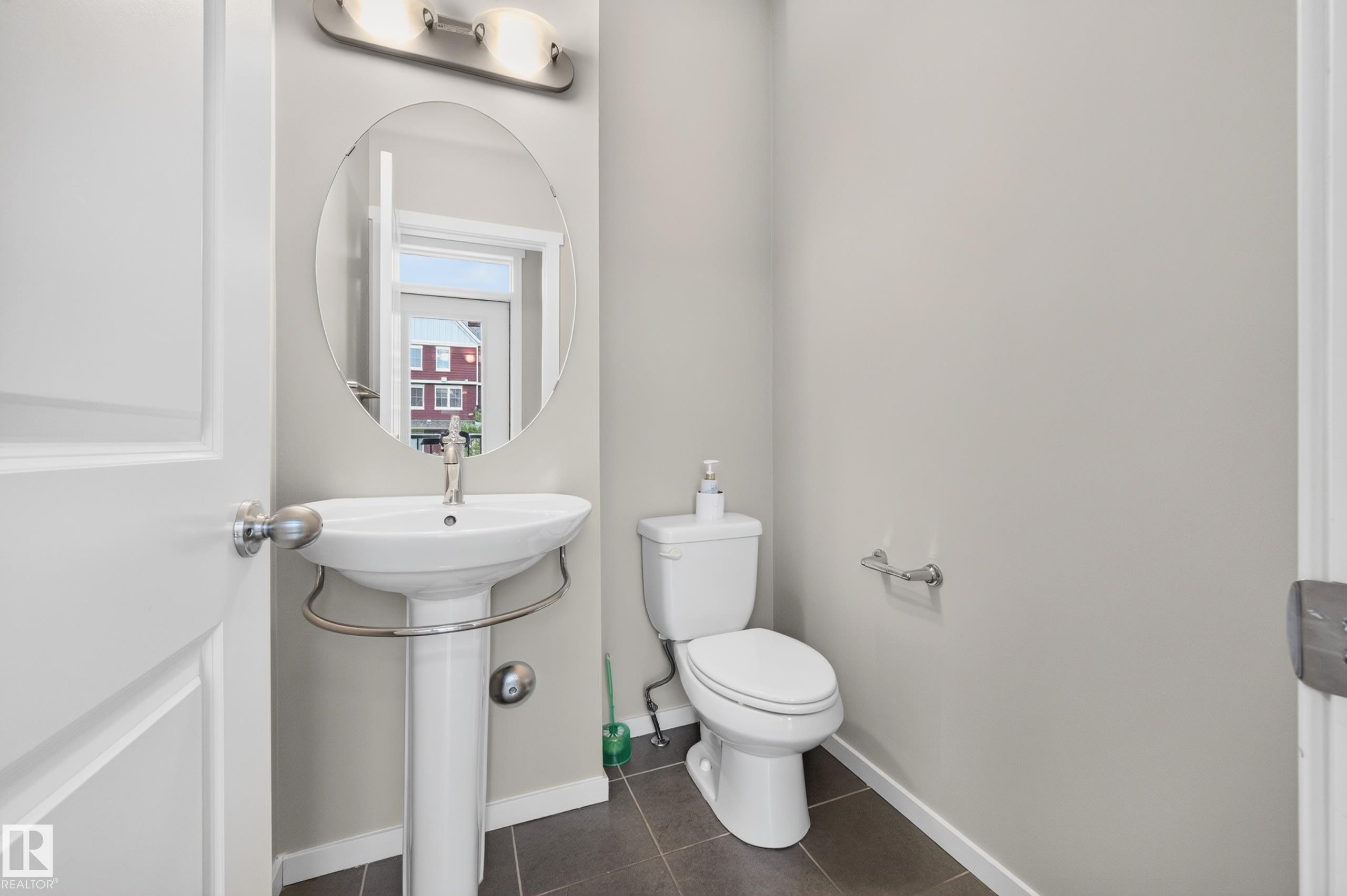 2 piece bath main floor. Pedestal sink with chrome faucet, oval wall-mounted mirror, brushed nickel vanity light fixture. - #72 603 Watt Bv Sw Sw, Edmonton, AB