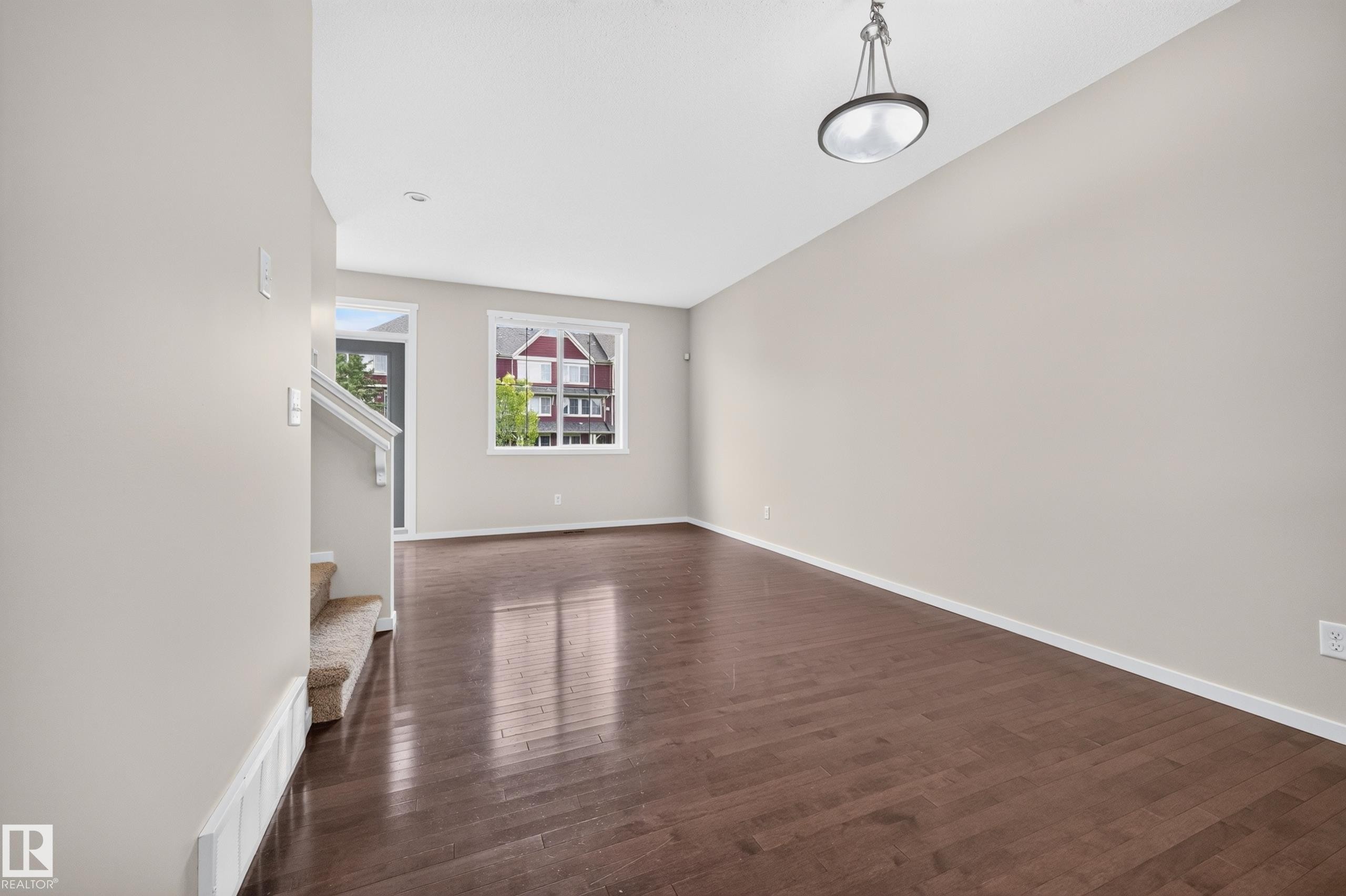 Wood-finish flooring, neutral wall tones, and recessed lighting create a versatile open space - #72 603 Watt Bv Sw Sw, Edmonton, AB