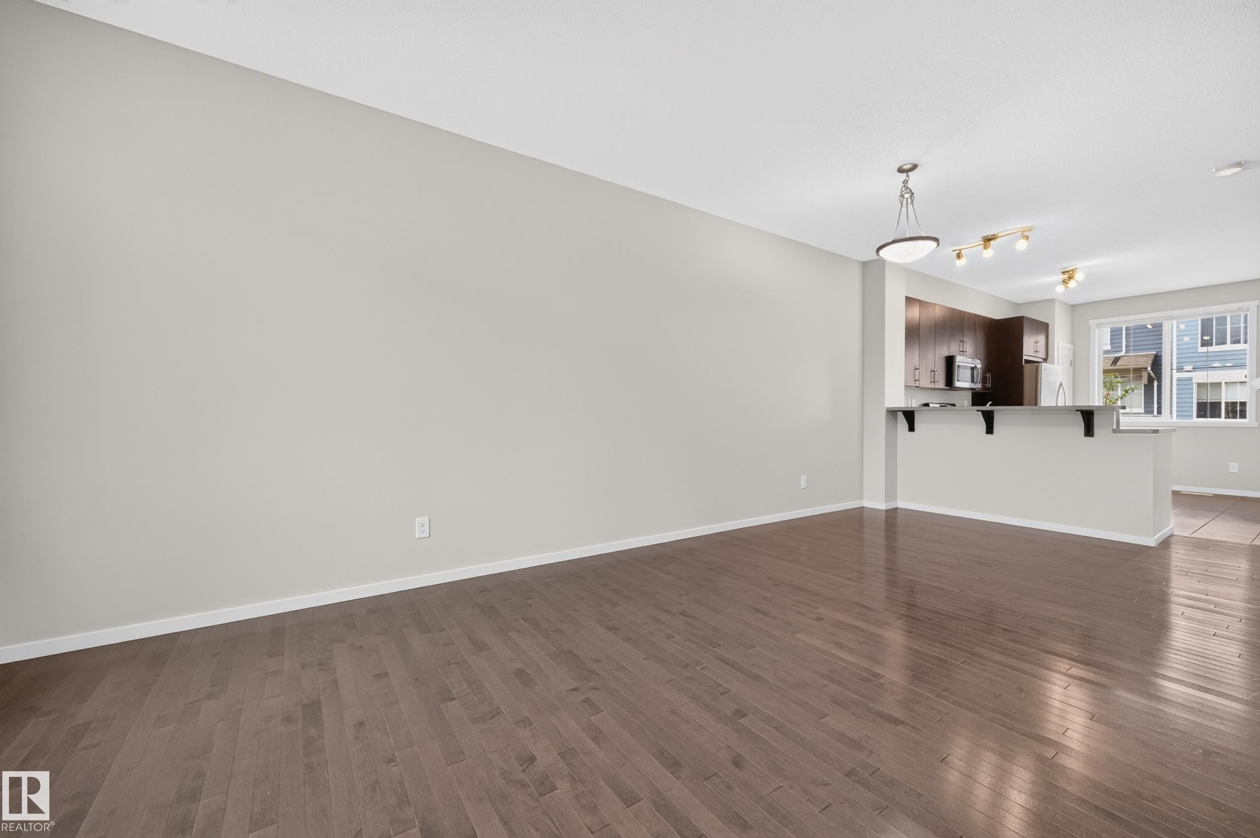 Hardwood flooring, recessed lighting, central pendant light fixture, dark wood cabinetry, stainless steel appliances - #72 603 Watt Bv Sw Sw, Edmonton, AB
