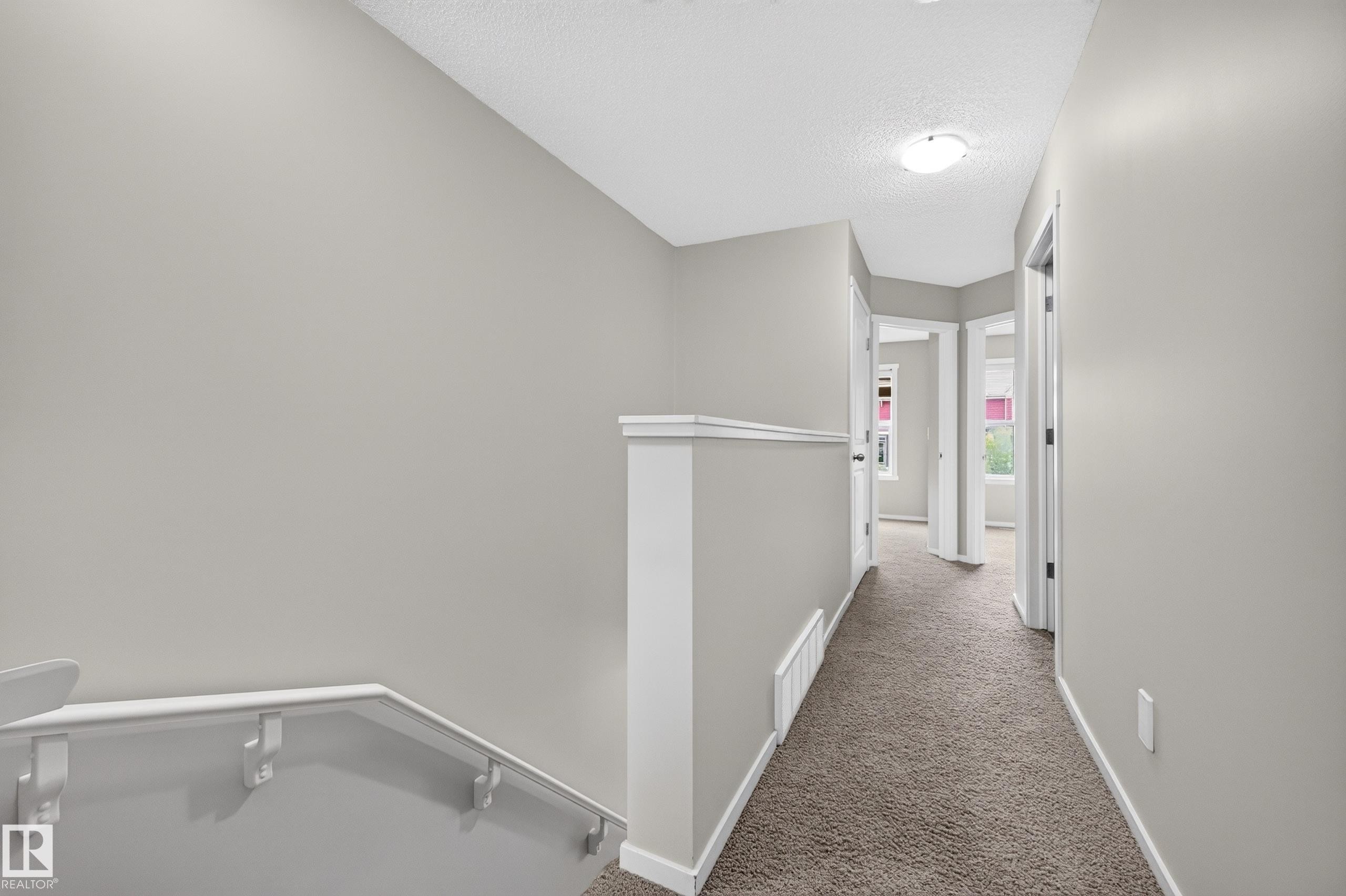 Carpeted hallway with light gray walls, white trim, and flush-mount lighting - #72 603 Watt Bv Sw Sw, Edmonton, AB