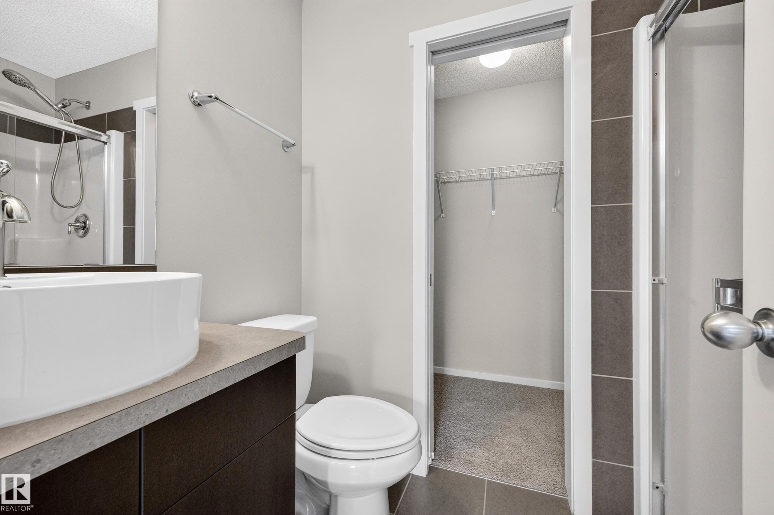 Modern vanity with a vessel sink, dark cabinetry, and a light-toned countertop - #72 603 Watt Bv Sw Sw, Edmonton, AB