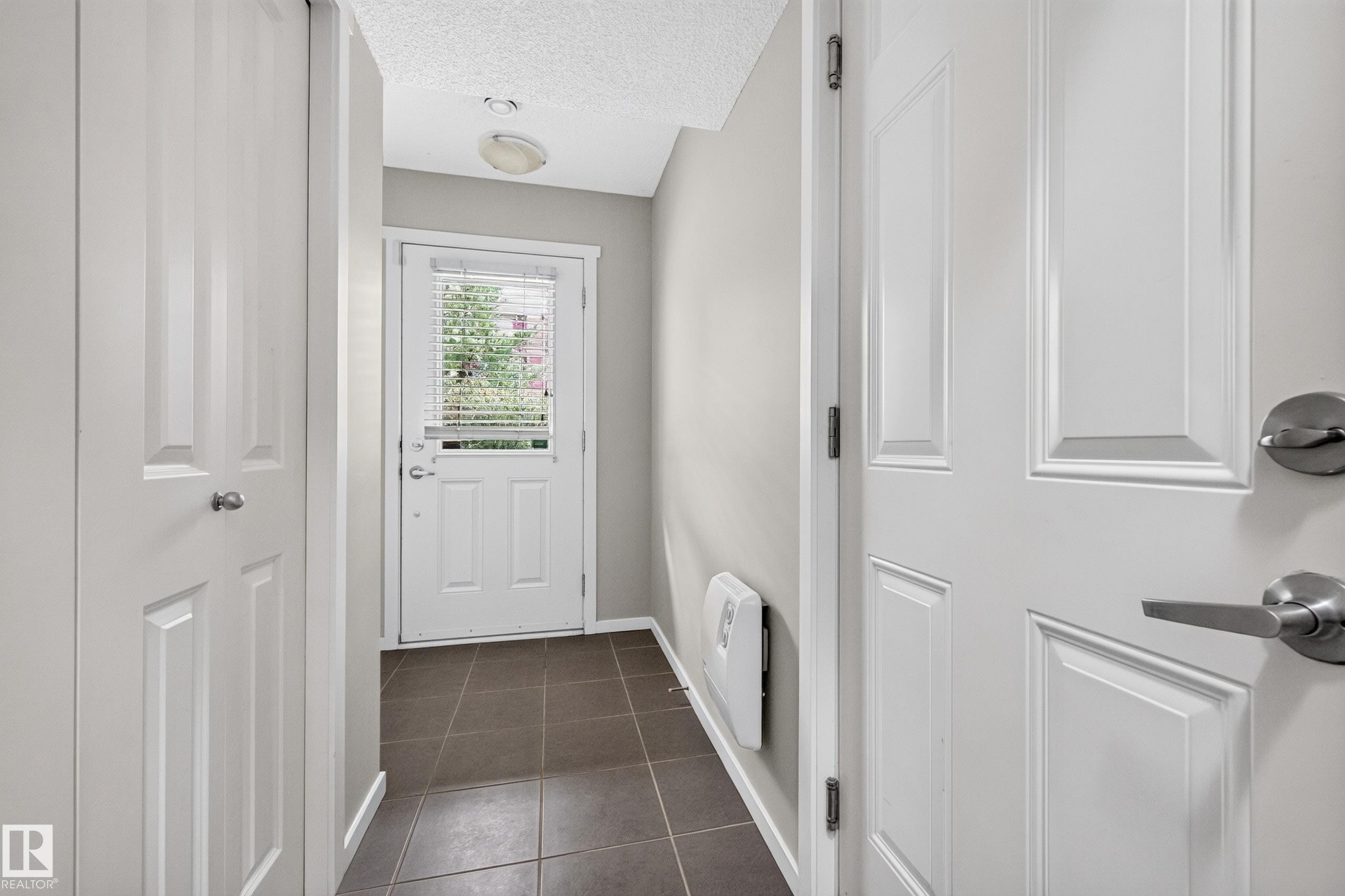 Tiled entry floor, white paneled doors, and ceiling-mounted light fixture - #72 603 Watt Bv Sw Sw, Edmonton, AB