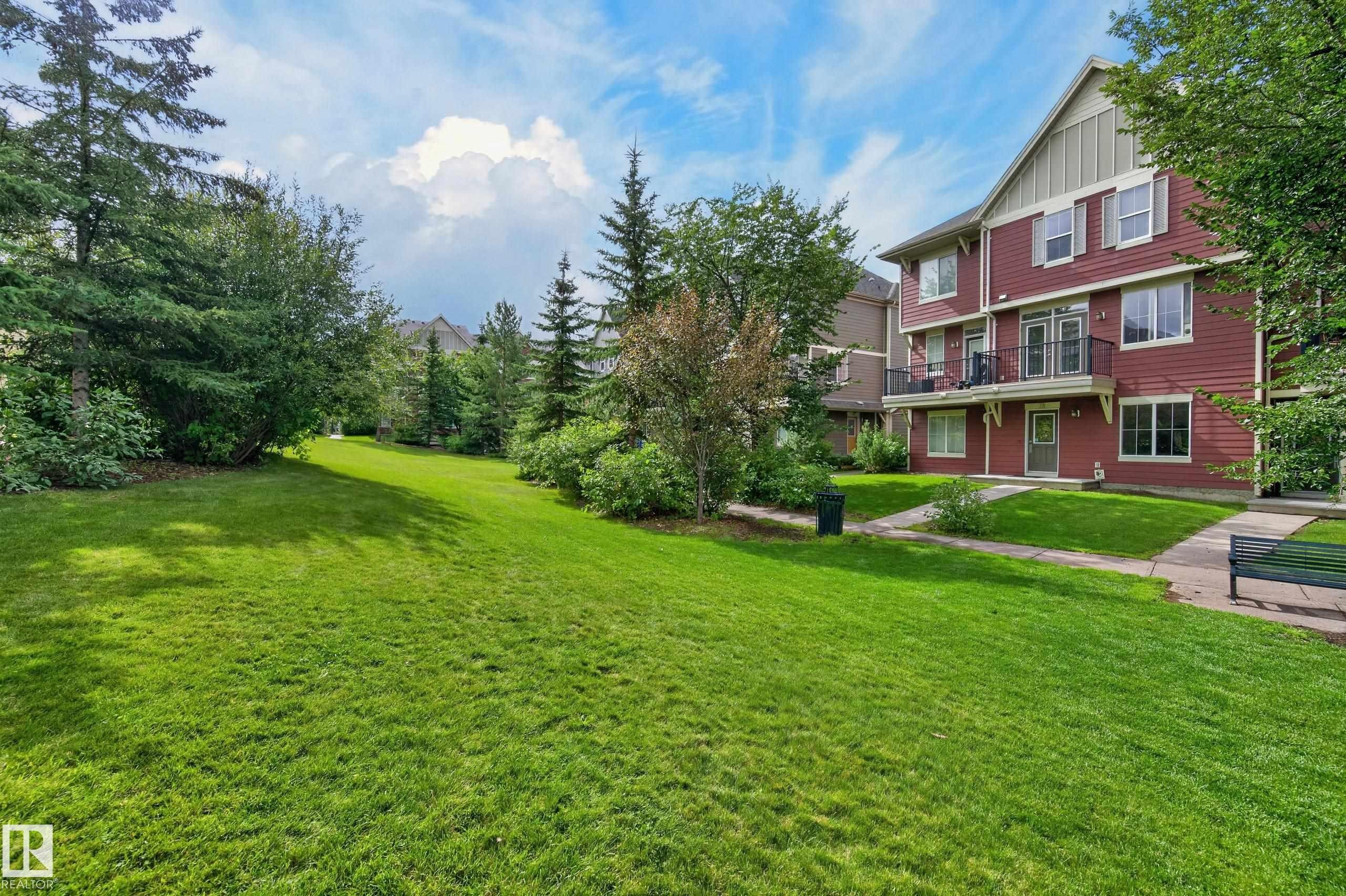 Red multi-story building featuring multiple balconies, a lower patio, and a light-colored gable - #72 603 Watt Bv Sw Sw, Edmonton, AB
