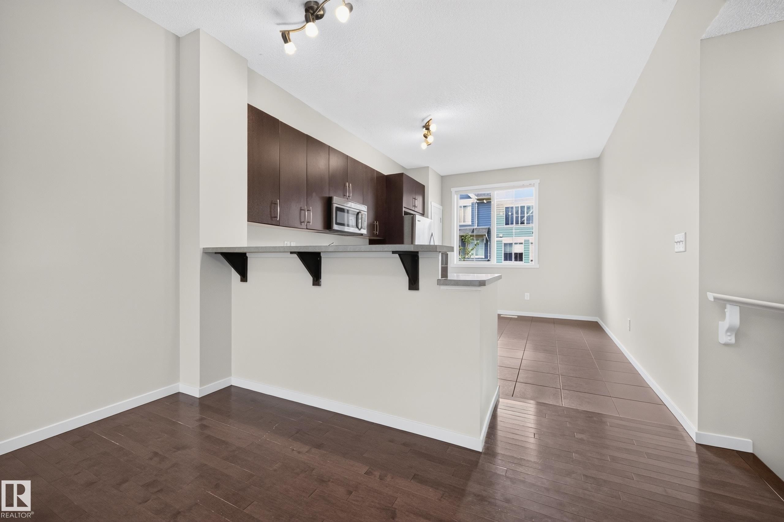 Kitchen with wood-finish cabinetry, stainless steel appliances, and a breakfast bar - #72 603 Watt Bv Sw Sw, Edmonton, AB