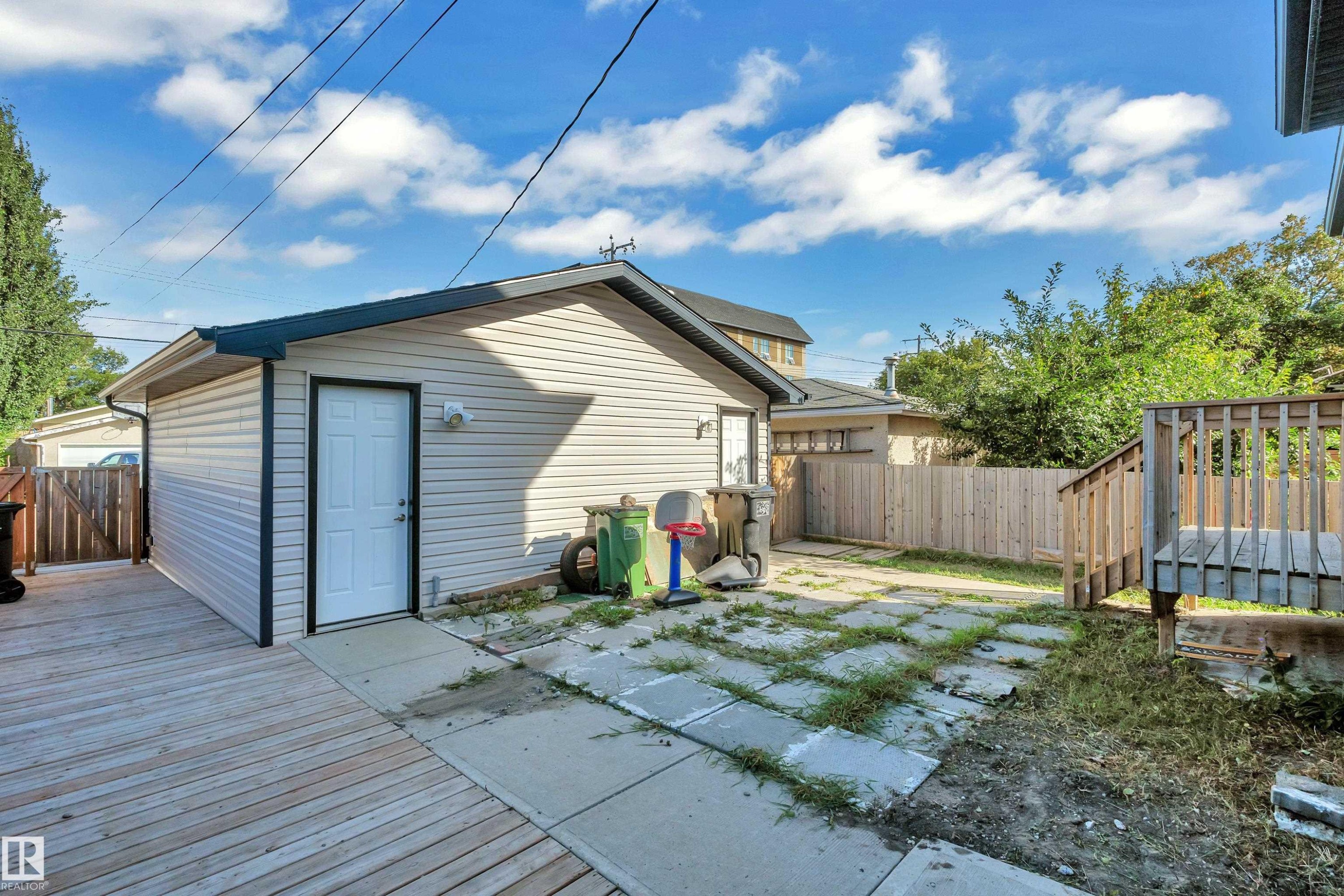 Detached garage with siding exterior, wood deck, wood privacy fencing, and concrete patio - 11421 82 Street Nw, Edmonton, AB