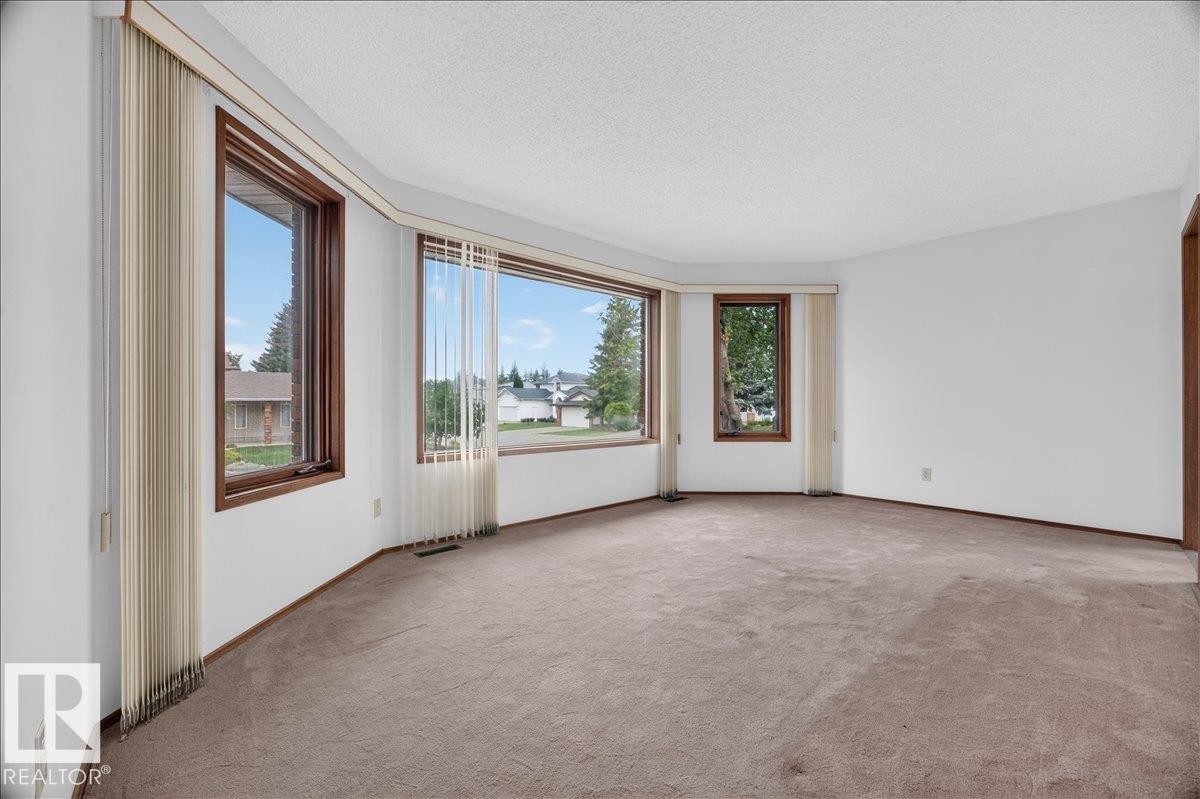 Bay window configuration with multiple windows, wood-finish window frames, and neutral carpeting - 2907 49 Street Nw, Edmonton, AB