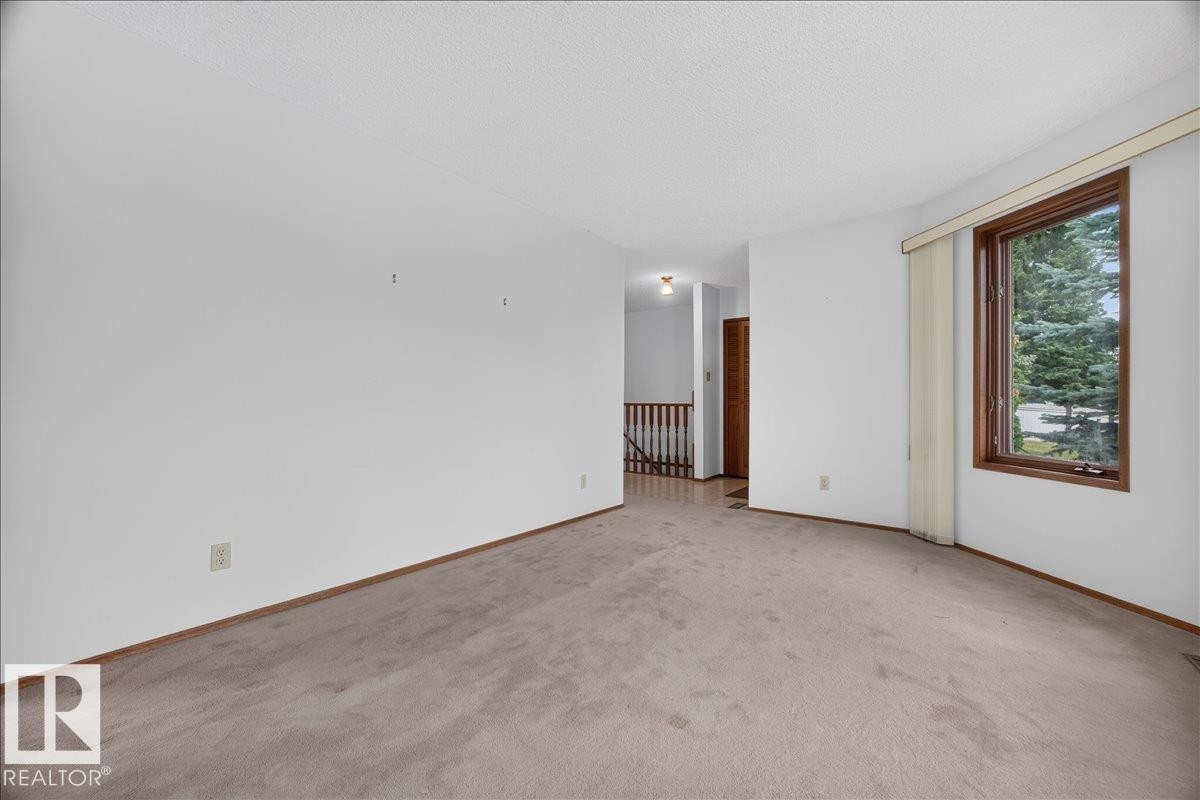 Wall-to-wall carpeting with solid baseboards, a wood-framed window, and a wooden banister - 2907 49 Street Nw, Edmonton, AB