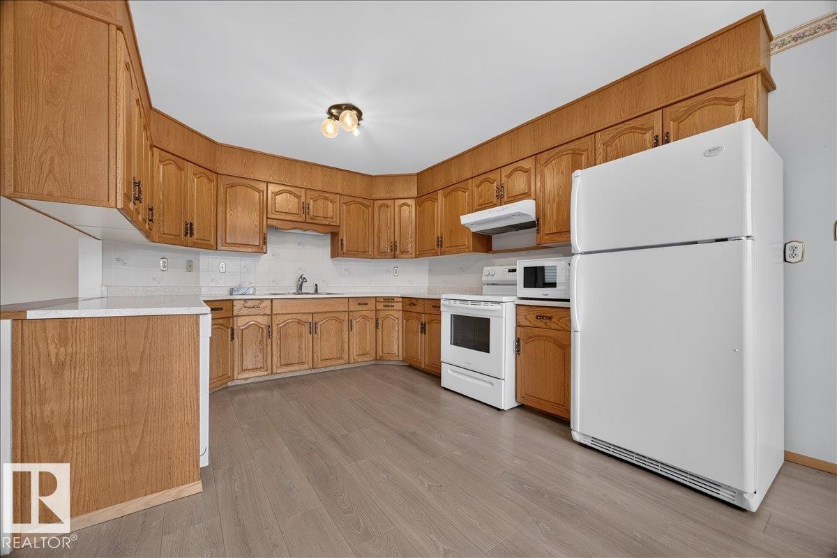 Kitchen featuring wood-finish cabinetry, white countertops, a white refrigerator, and wood-finish flooring - 2907 49 Street Nw, Edmonton, AB
