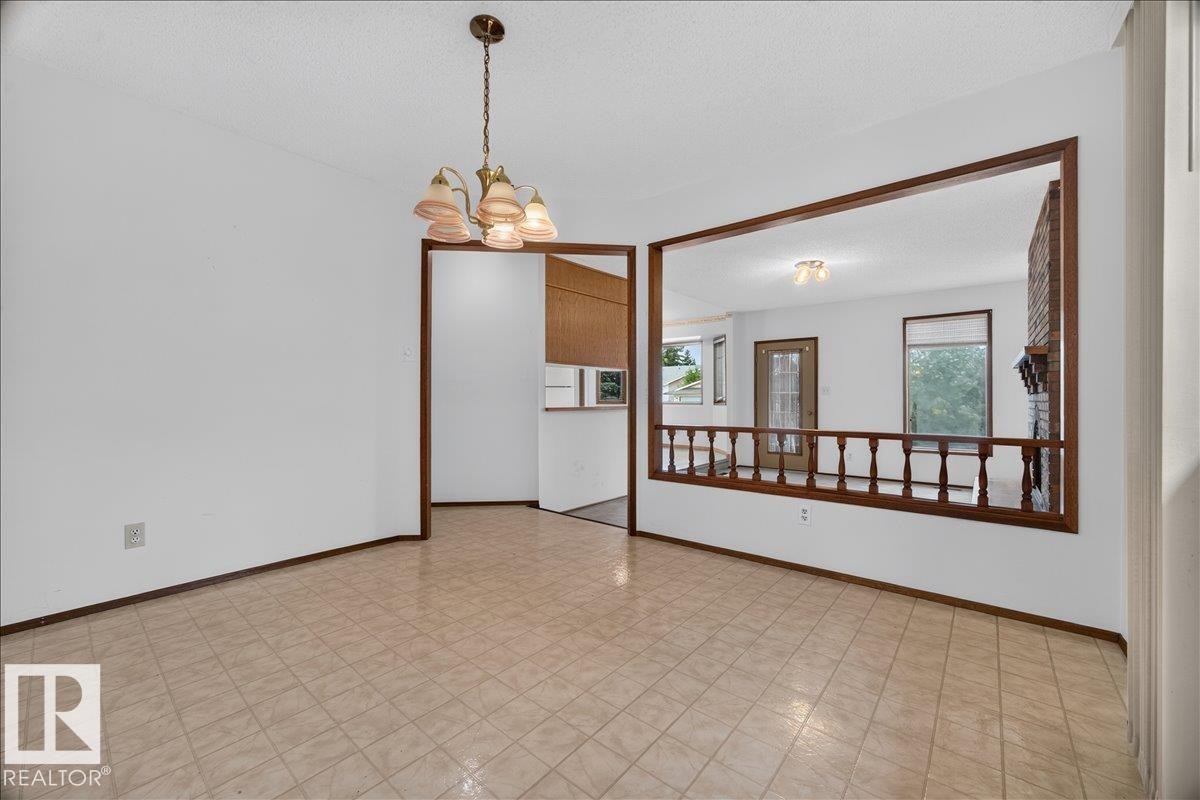 Tile flooring, suspended chandelier, wood-trimmed archway, interior wood balustrade, and brick fireplace - 2907 49 Street Nw, Edmonton, AB