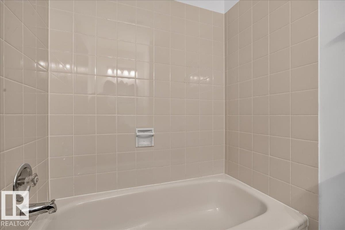 Bathtub with integrated soap dish, chrome fixtures, and square tile surround - 2907 49 Street Nw, Edmonton, AB