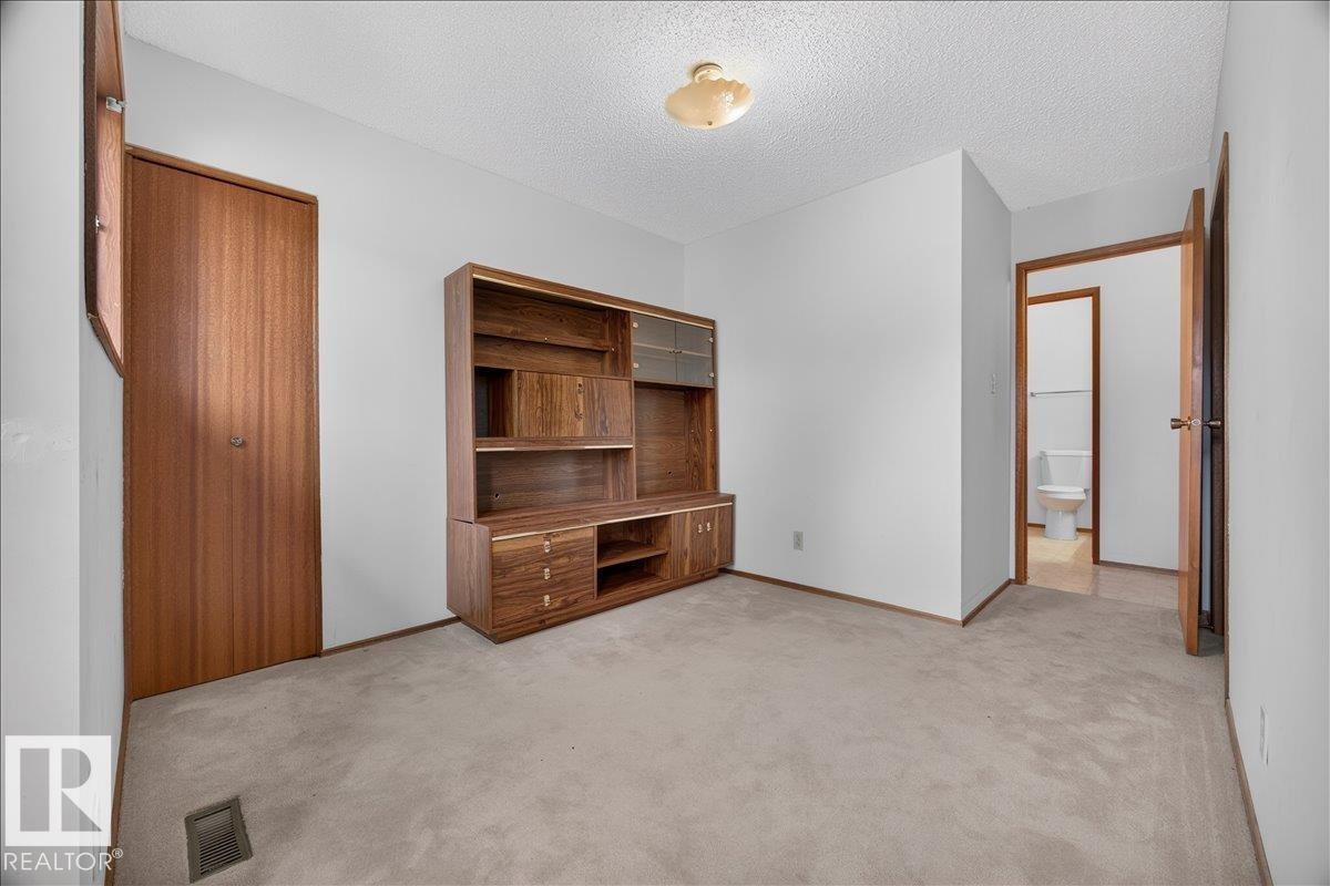 Recessed ceiling light fixture, wood-finish doors, built-in wooden shelving unit with cabinet storage, light neutral-toned carpeting, and white wall finishes - 2907 49 Street Nw, Edmonton, AB