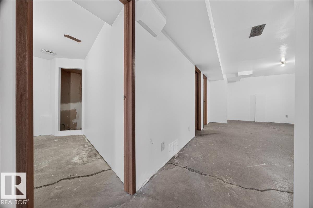 Open layout with concrete flooring, white walls, and wood-finish door frames - 2907 49 Street Nw, Edmonton, AB