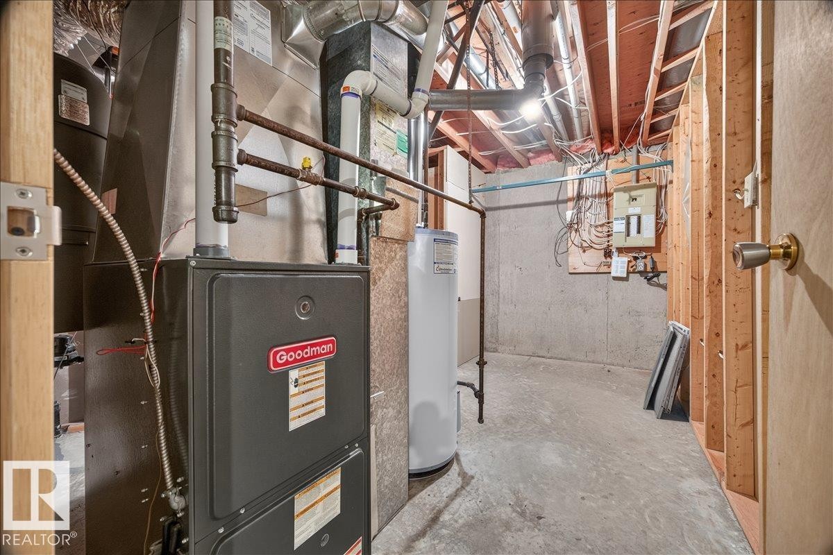 Utility room featuring a furnace, water heater, exposed wood framing, and concrete flooring - 2907 49 Street Nw, Edmonton, AB