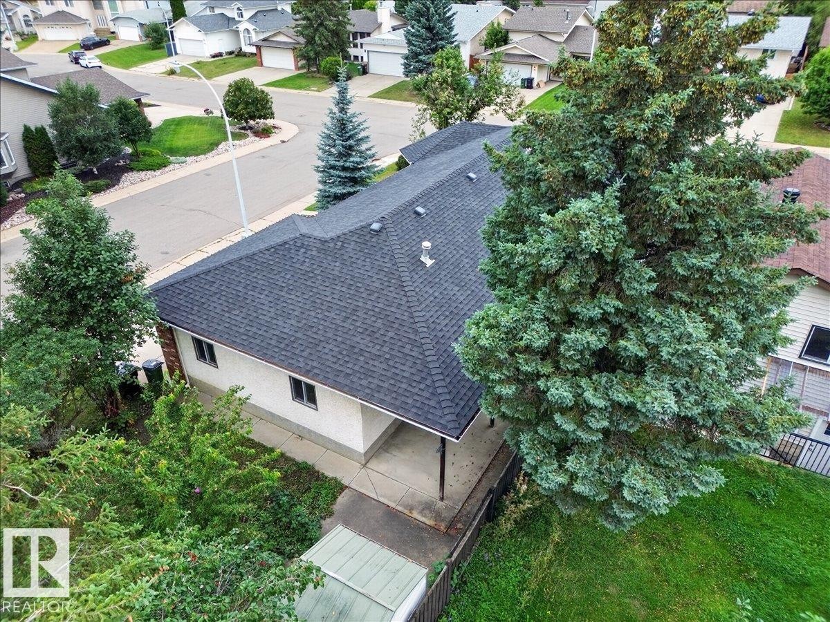 Shingled roofline, light-toned exterior siding, multiple windows, established trees, and a concrete driveway - 2907 49 Street Nw, Edmonton, AB