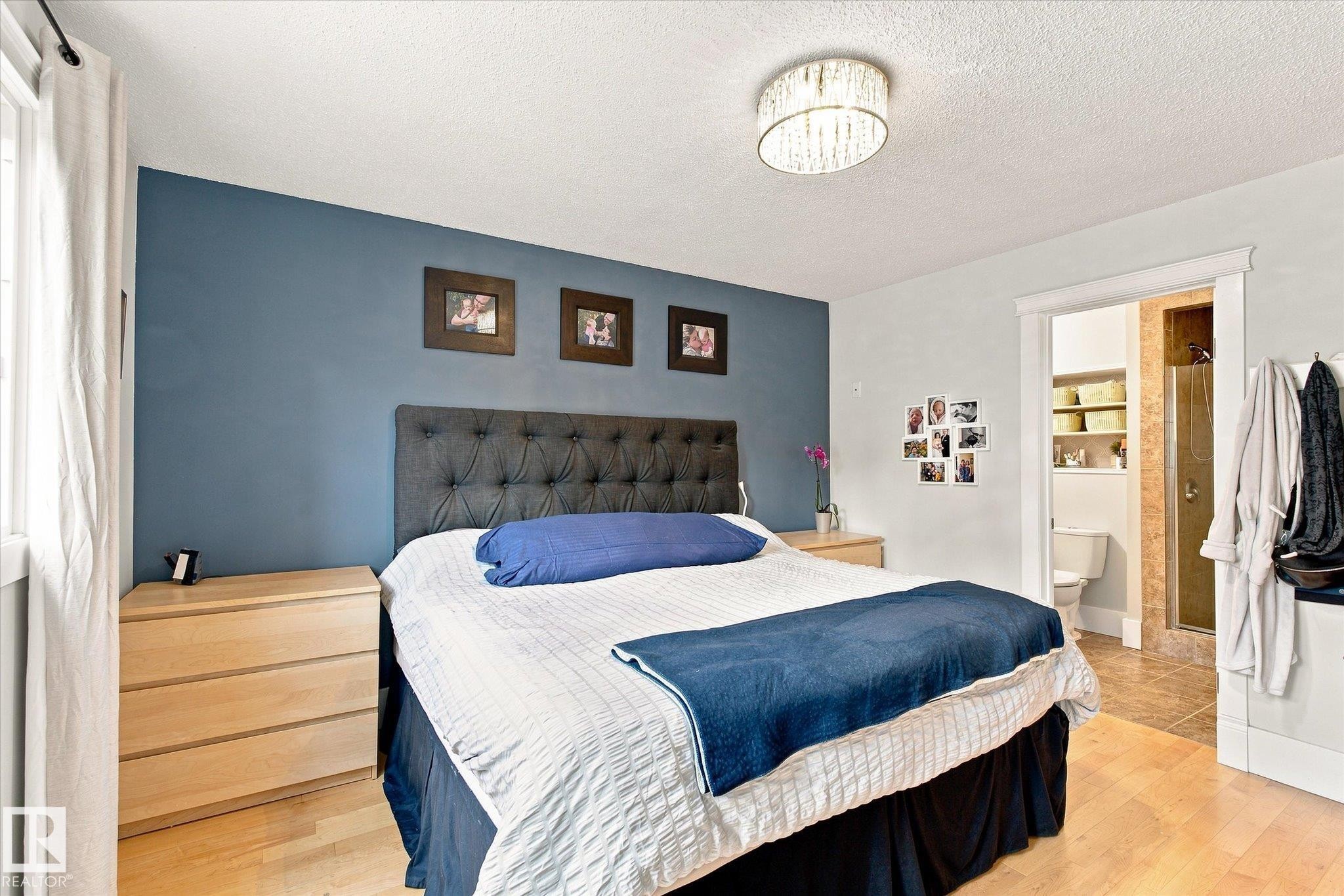 Hardwood-style flooring, tufted headboard, recessed doorway, tiled bathroom flooring, and a ceiling-mounted light fixture - 3 Akins Drive, St. Albert, AB