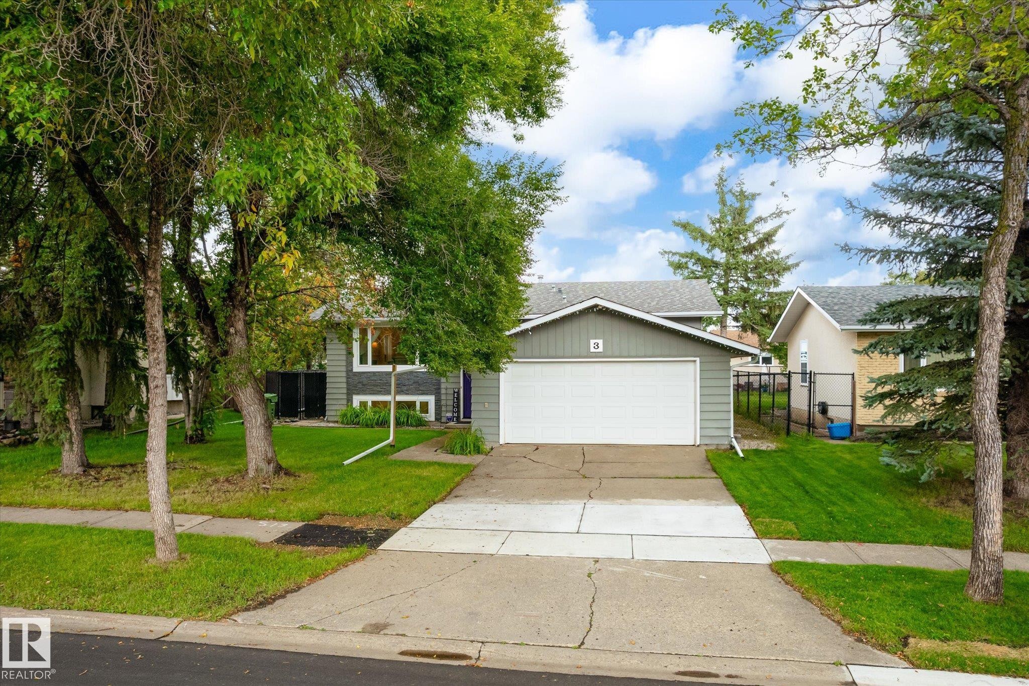 Attached front-facing garage with a white door, light gray siding, and a gabled roof - 3 Akins Drive, St. Albert, AB