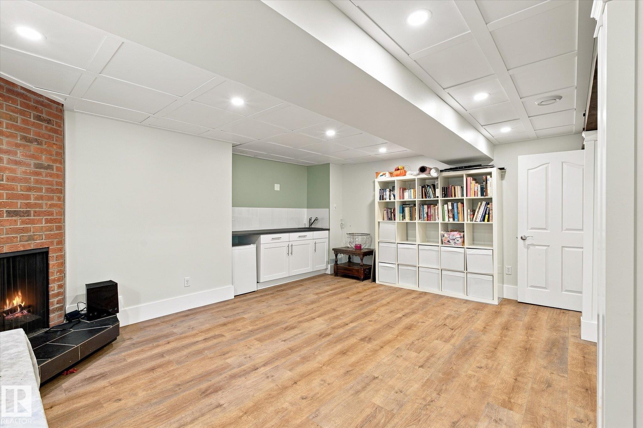 Wood-finish flooring, recessed lighting, brick-clad fireplace, built-in wet bar, and coffered ceiling - 3 Akins Drive, St. Albert, AB