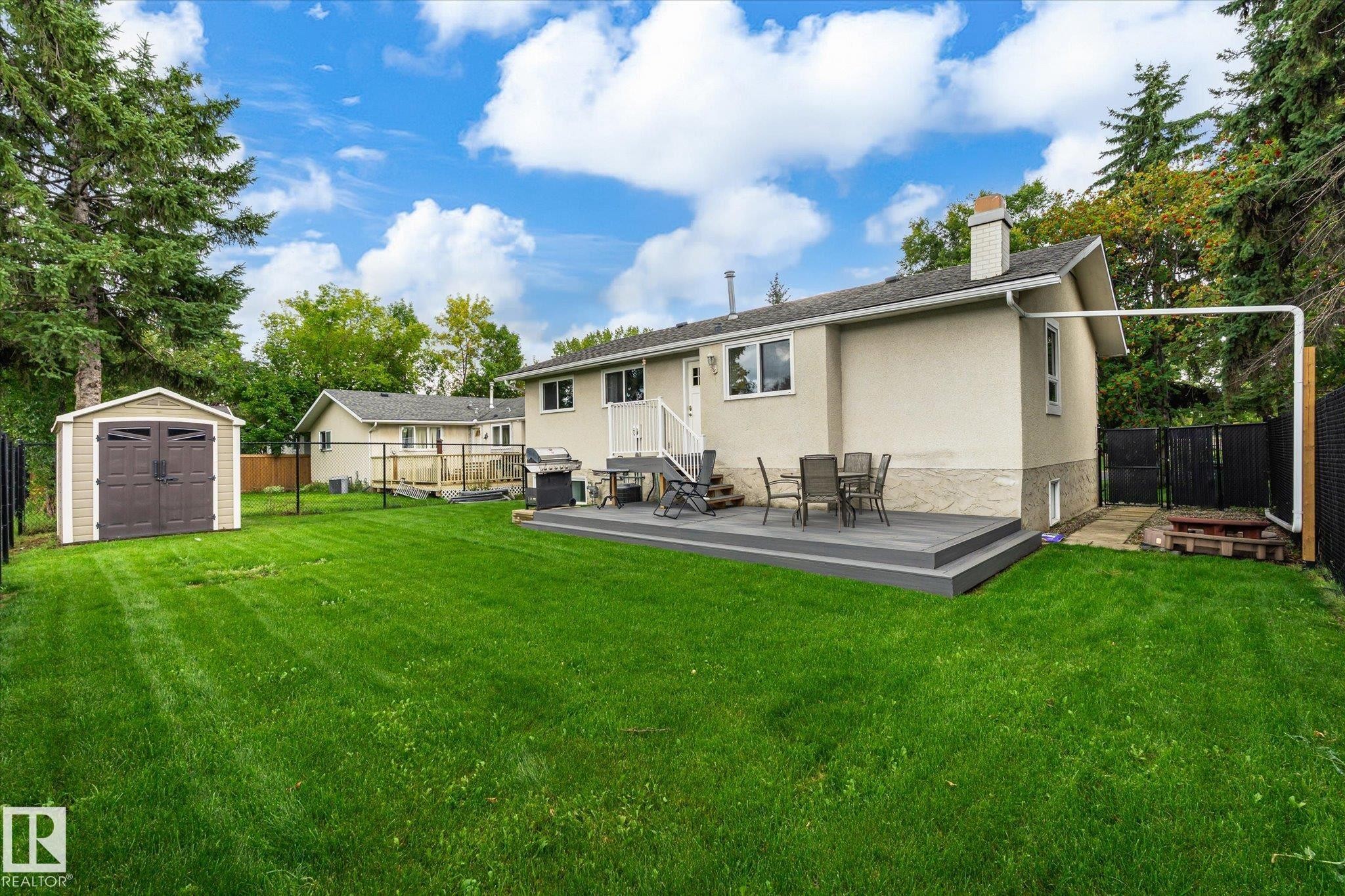 Expansive backyard featuring a shed, composite deck, mature trees, and privacy fencing - 3 Akins Drive, St. Albert, AB