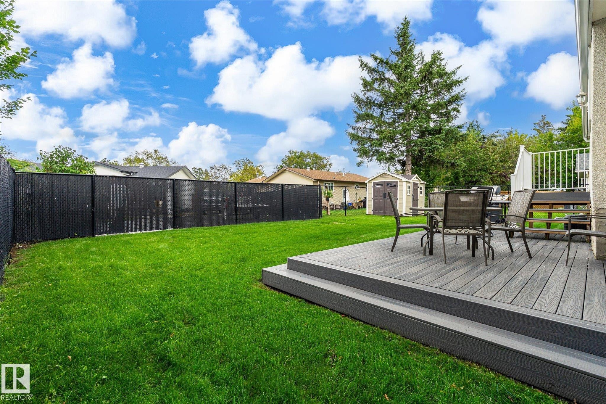 Expansive backyard featuring a manicured lawn, a multi-tiered composite deck, and a privacy fence - 3 Akins Drive, St. Albert, AB