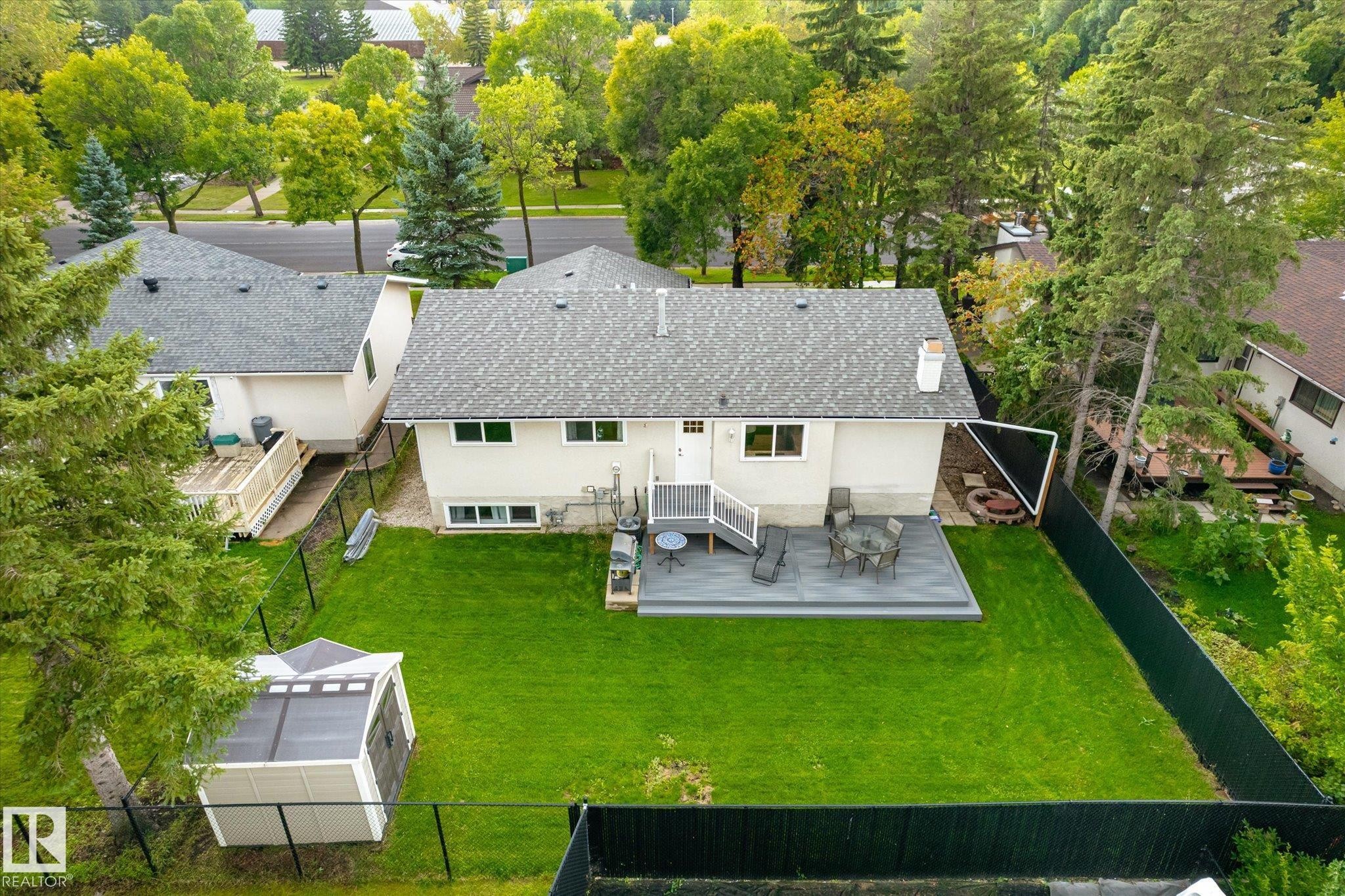 Expansive backyard featuring a manicured lawn, composite decking, and a fire pit area - 3 Akins Drive, St. Albert, AB