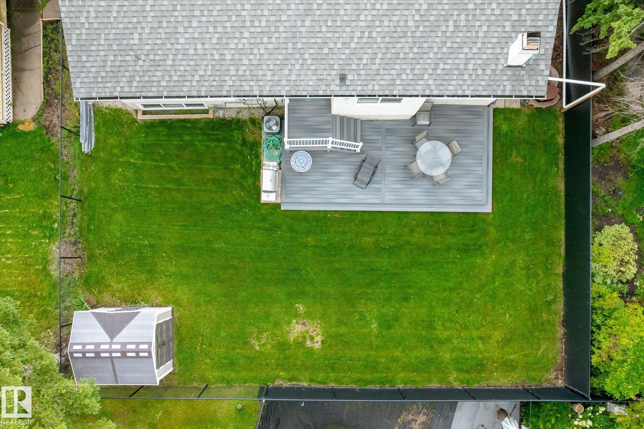Expansive backyard featuring a large composite deck, mature green lawn, and full perimeter fencing - 3 Akins Drive, St. Albert, AB
