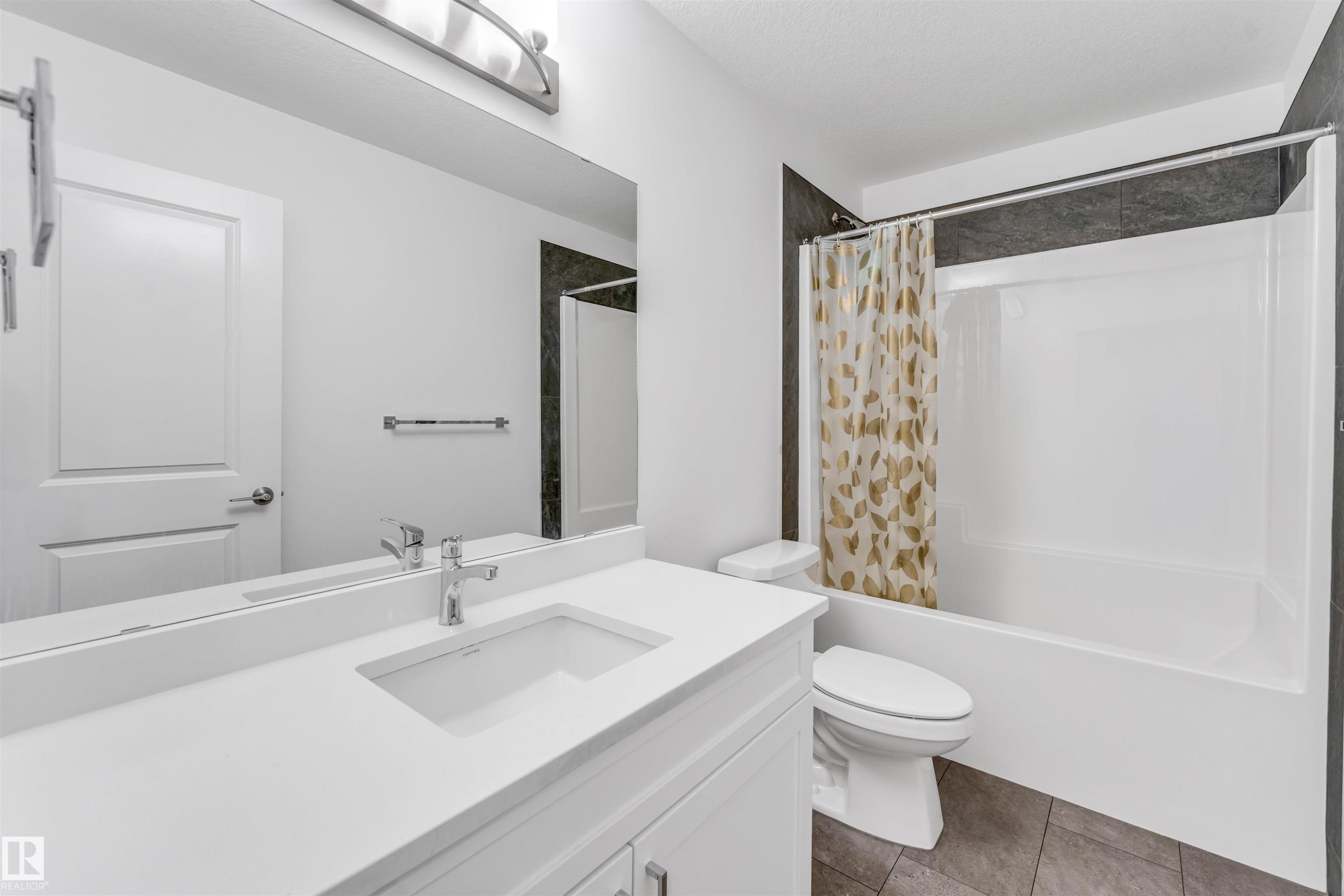 White vanity with an integrated sink and chrome faucet, large mirror, and overhead light fixture - #45 2710 66 St Sw, Edmonton, AB