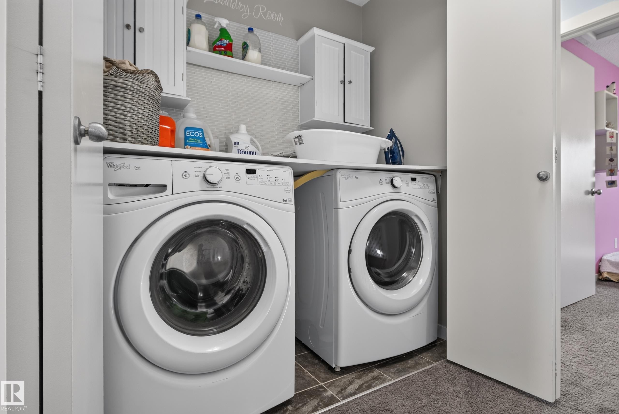 Dedicated laundry area featuring a front-loading washer and dryer, built-in shelving, and upper cabinetry - 17363 120 Street Nw, Edmonton, AB