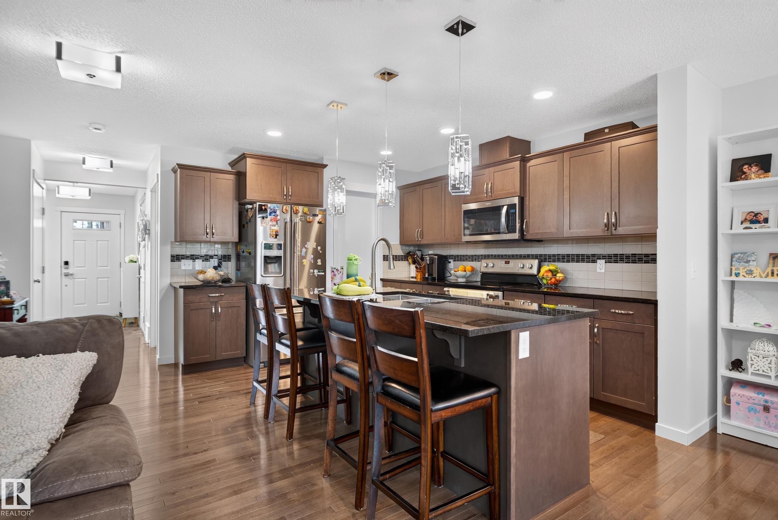 Chef's kitchen featuring rich wood cabinetry, stainless steel appliances, granite countertops, and a center island with seating - 17363 120 Street Nw, Edmonton, AB