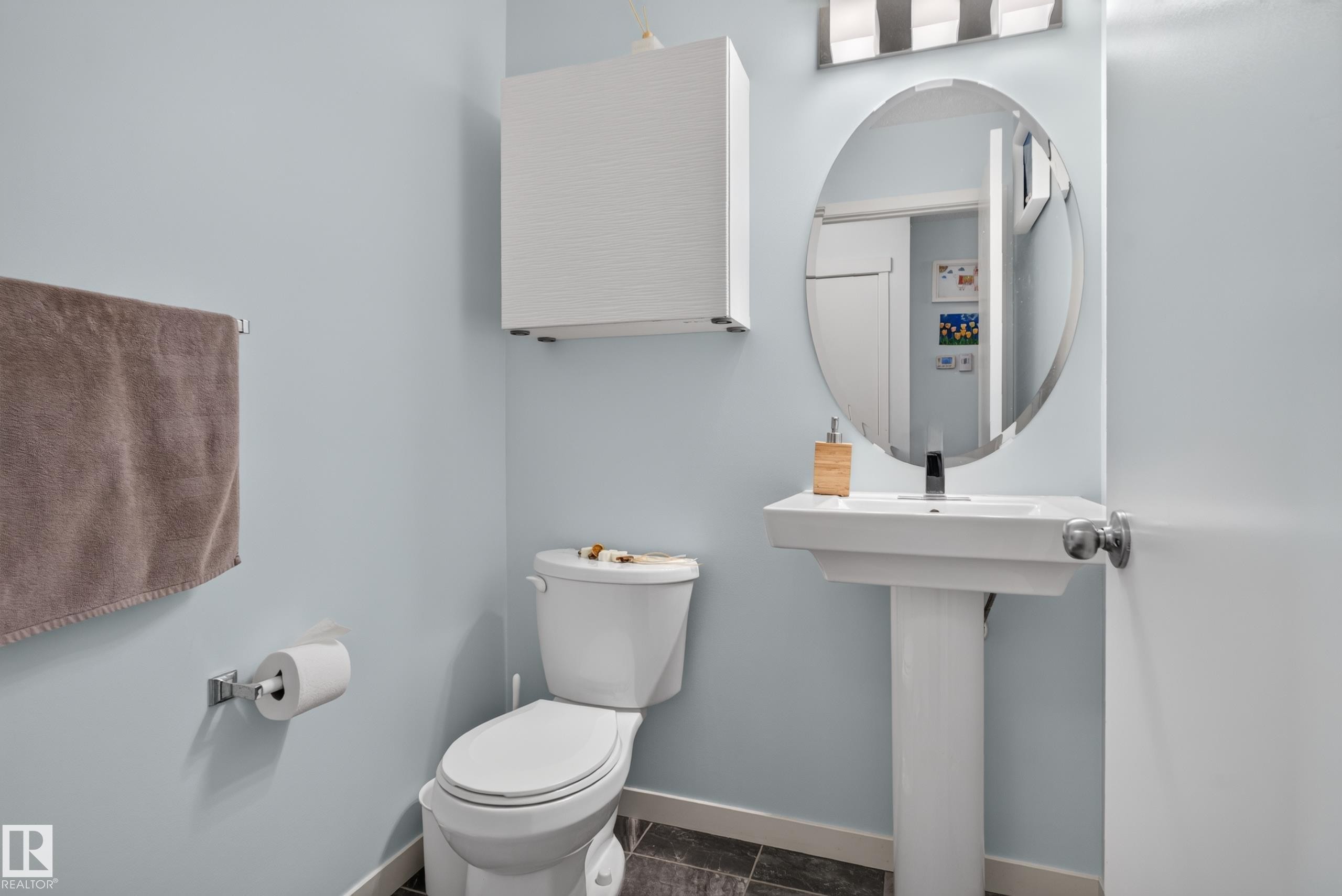 Pedestal sink with an oval mirror, wall-mounted storage cabinet, and chrome fixtures - 17363 120 Street Nw, Edmonton, AB