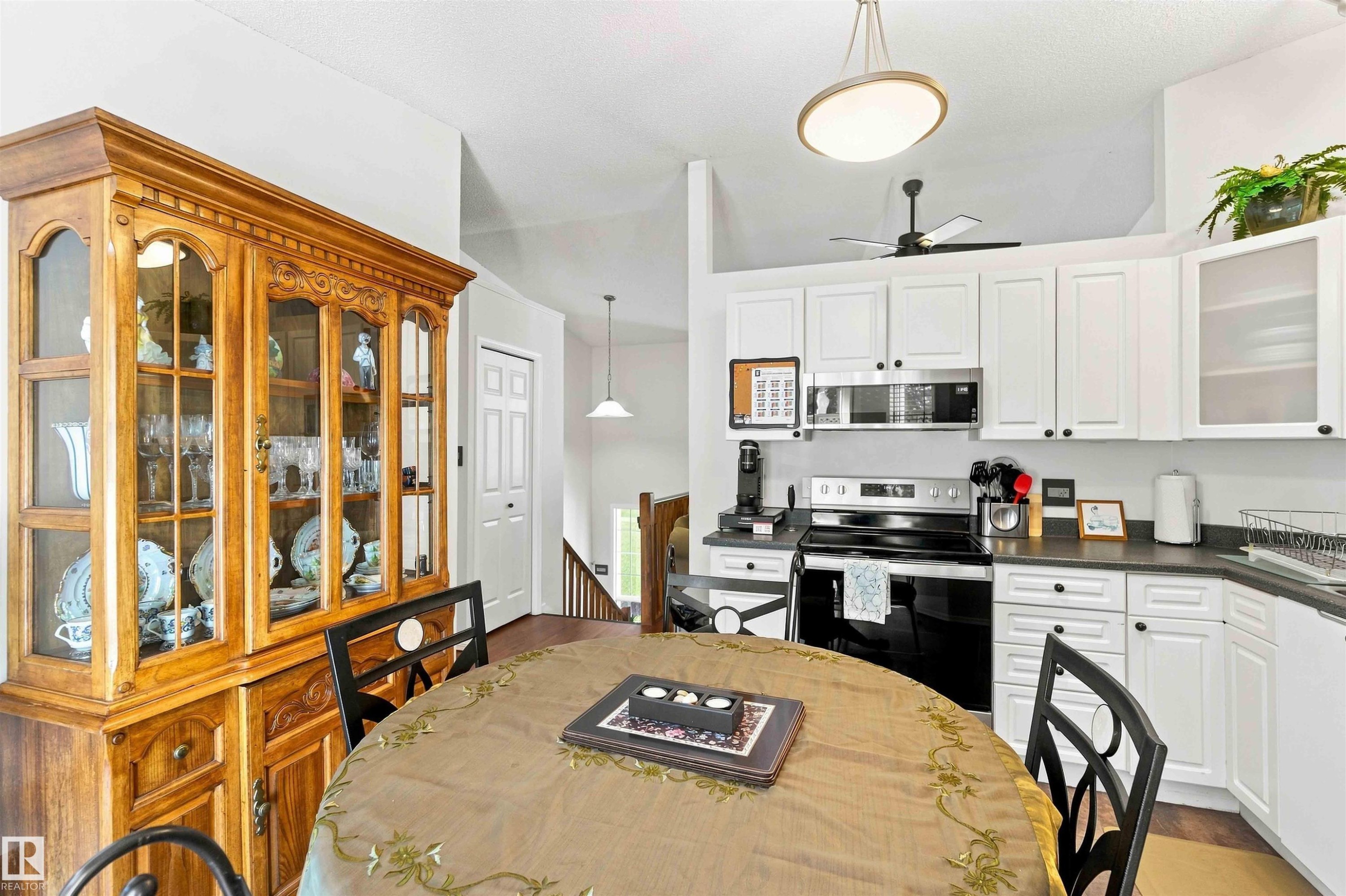 Kitchen featuring white cabinetry, dark countertops, a stainless steel microwave, and a built-in range - #6 15 Poirier Av, St. Albert, AB