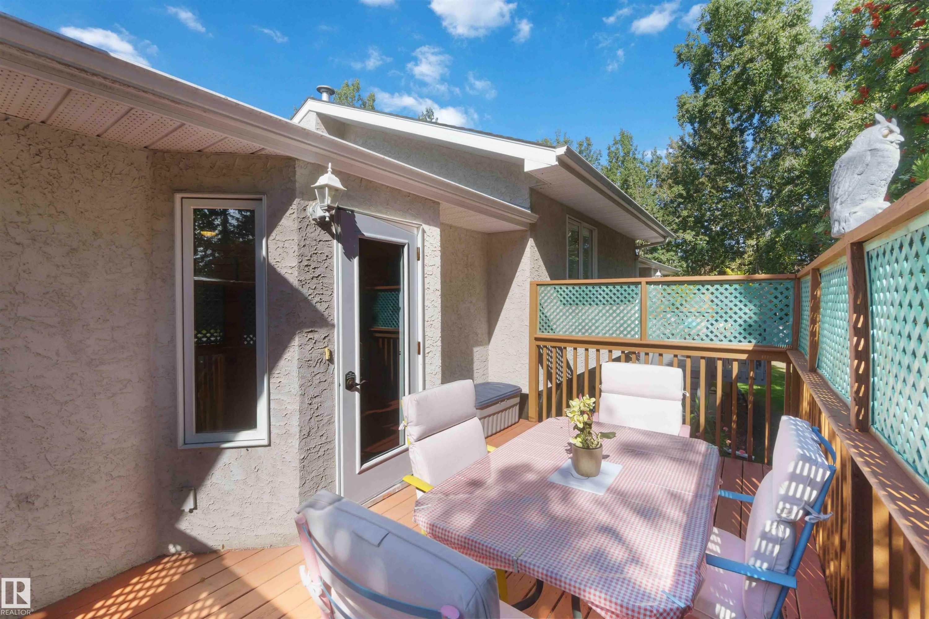 Wood-plank deck with lattice privacy screens, stucco exterior, and painted trim - #6 15 Poirier Av, St. Albert, AB