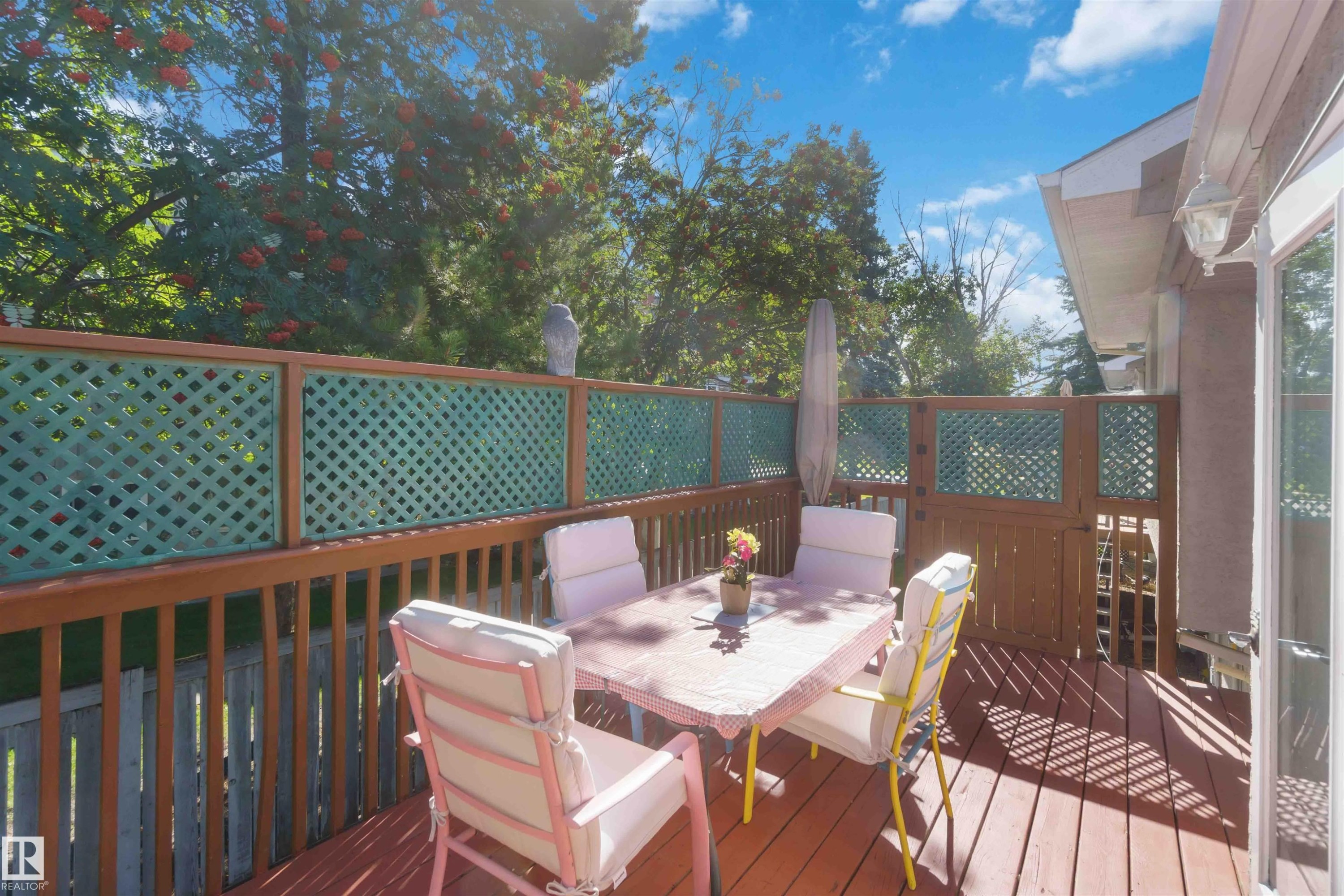 Wood-finish deck with lattice privacy screening, direct access to the interior, and mature perimeter trees - #6 15 Poirier Av, St. Albert, AB