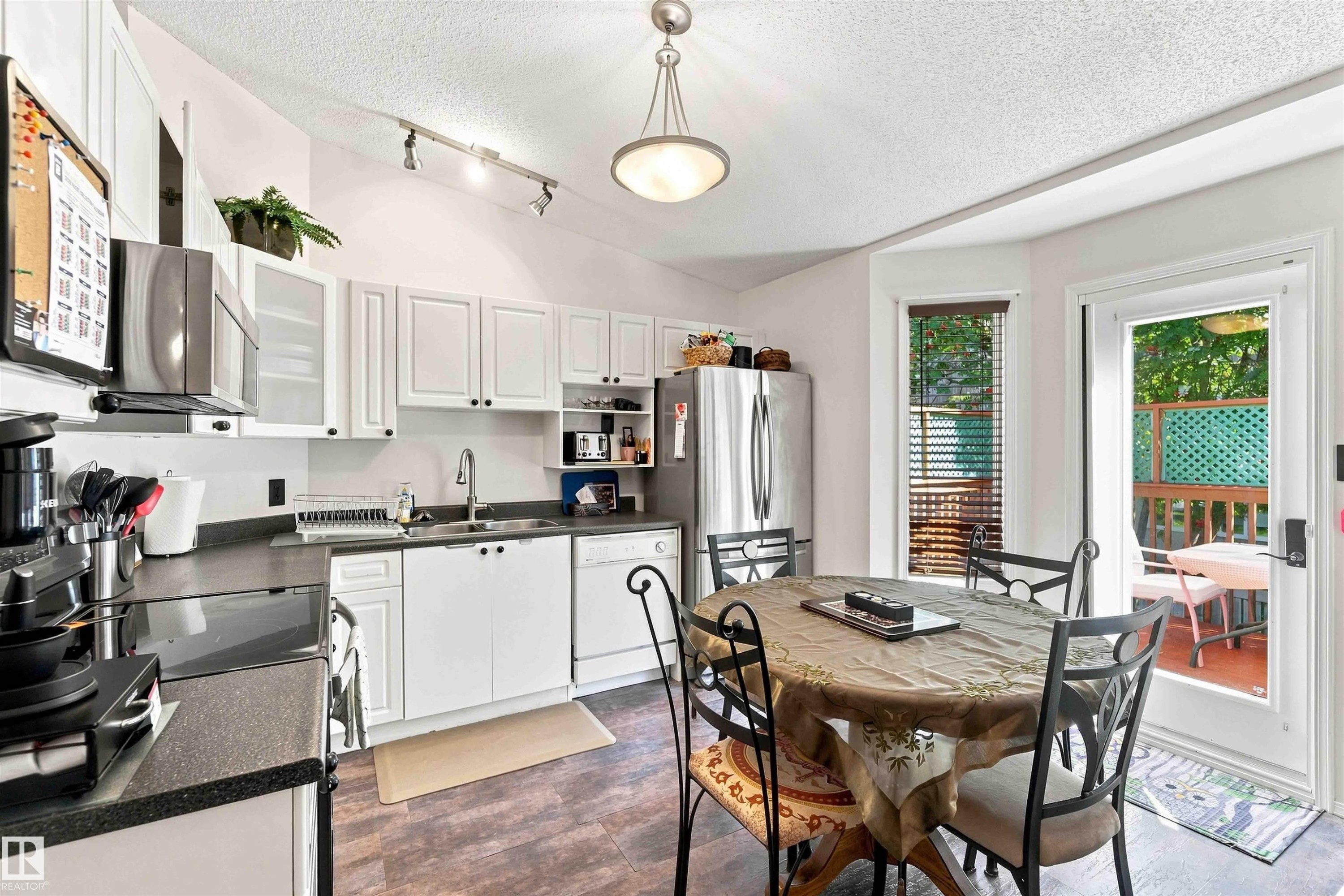 White cabinetry, dark countertops, wood-finish flooring, stainless steel appliances, and outdoor access - #6 15 Poirier Av, St. Albert, AB