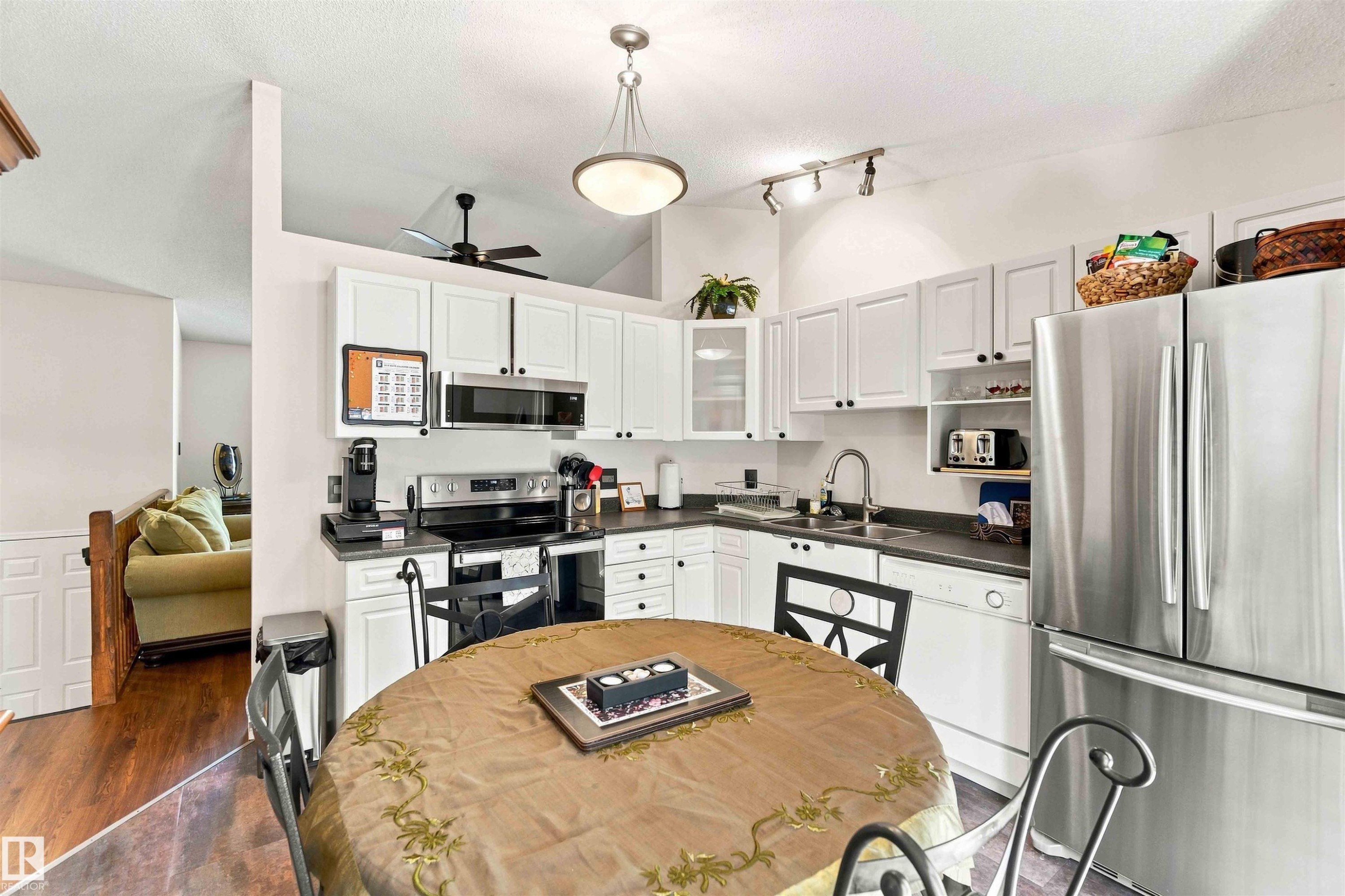 White shaker-style cabinetry, stainless steel appliances, dark countertops, vaulted ceiling, and recessed lighting - #6 15 Poirier Av, St. Albert, AB