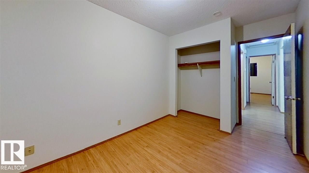 Wood-finish flooring throughout, bright white walls, and an open closet space with shelving - 4611 52 Avenue, Stony Plain, AB