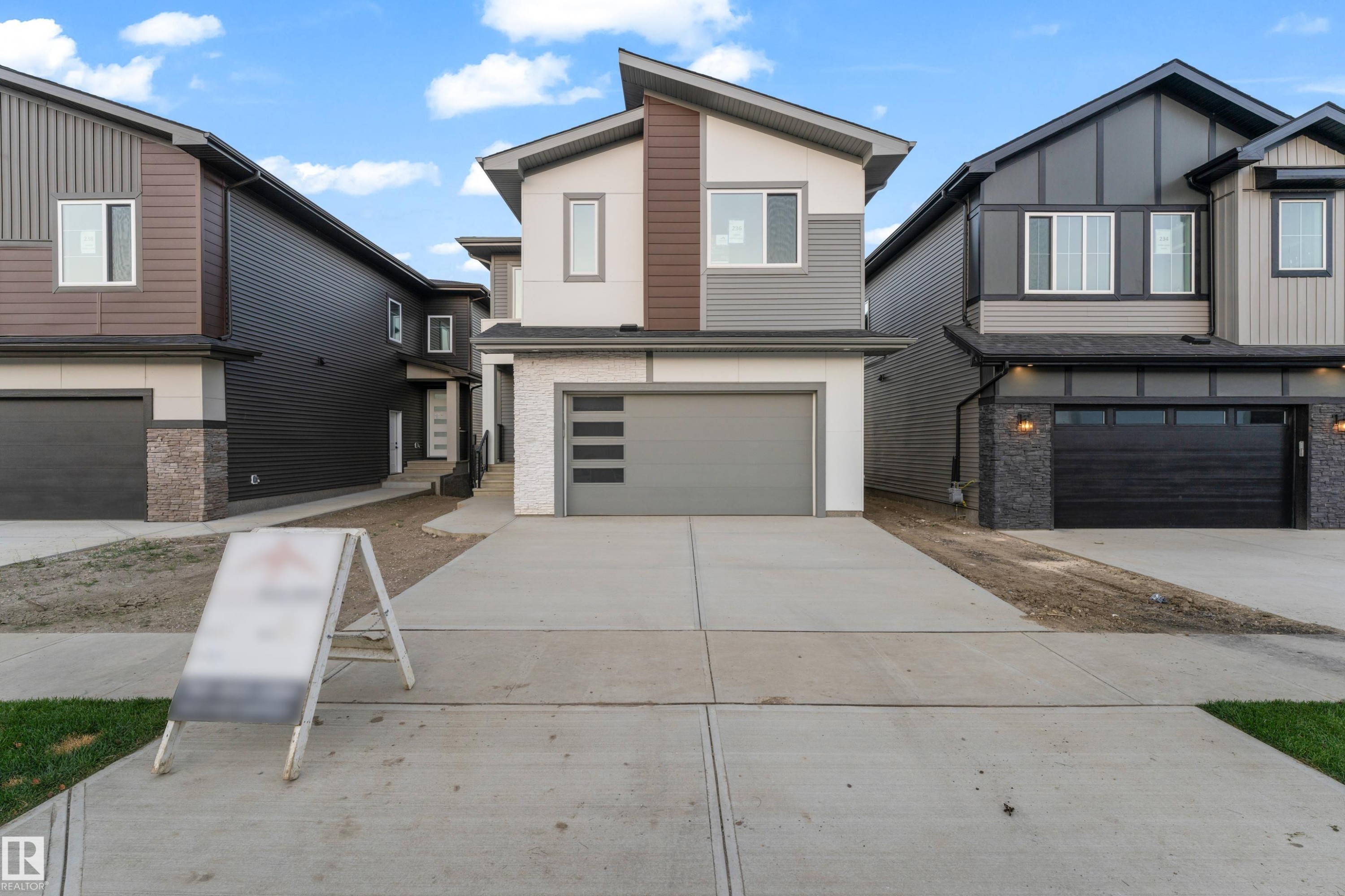 Modern exterior with multi-tone siding, a prominent attached garage, and a concrete driveway - 236 Linden Loop, Leduc, AB